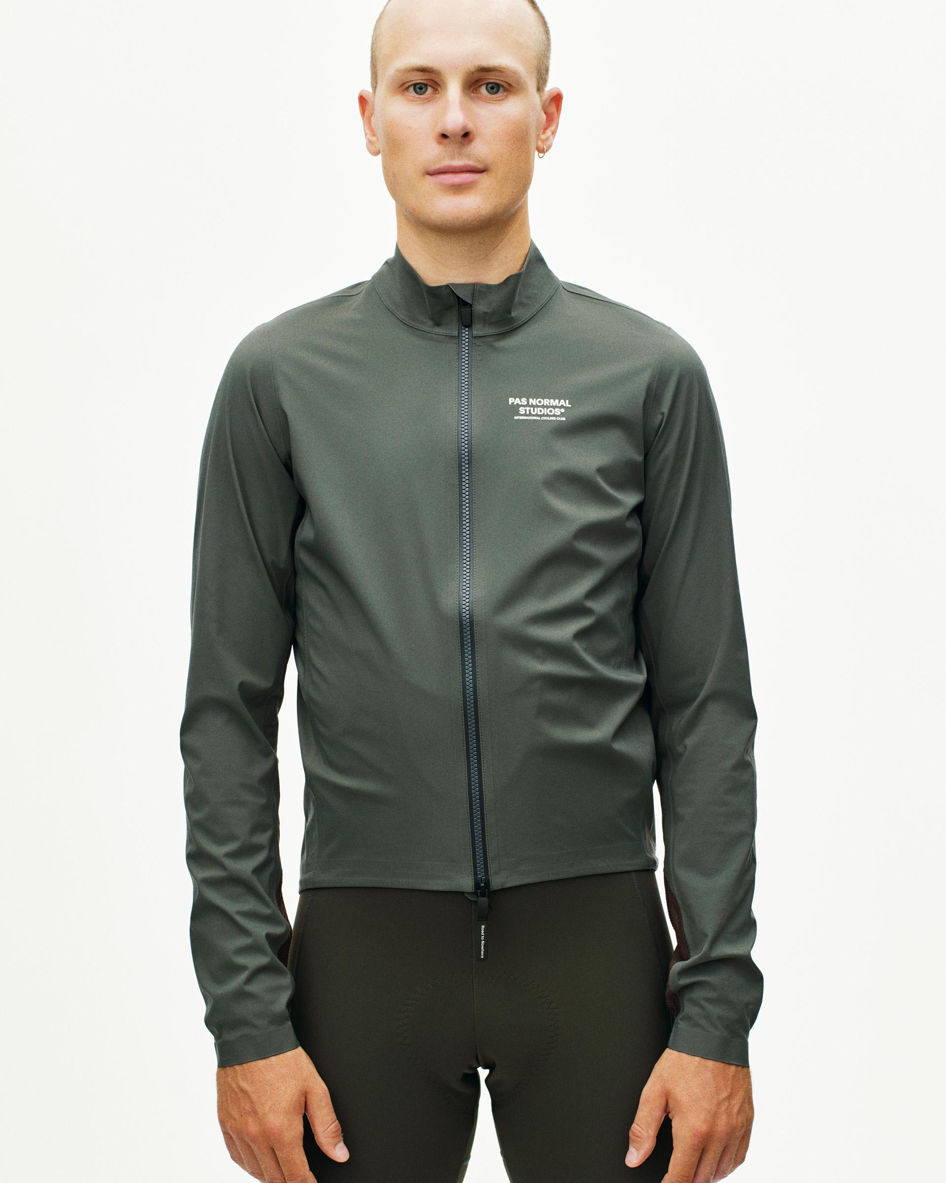 Dark Grey Mechanism Shell cycling jacket on model, front view with full zip and white chest logo