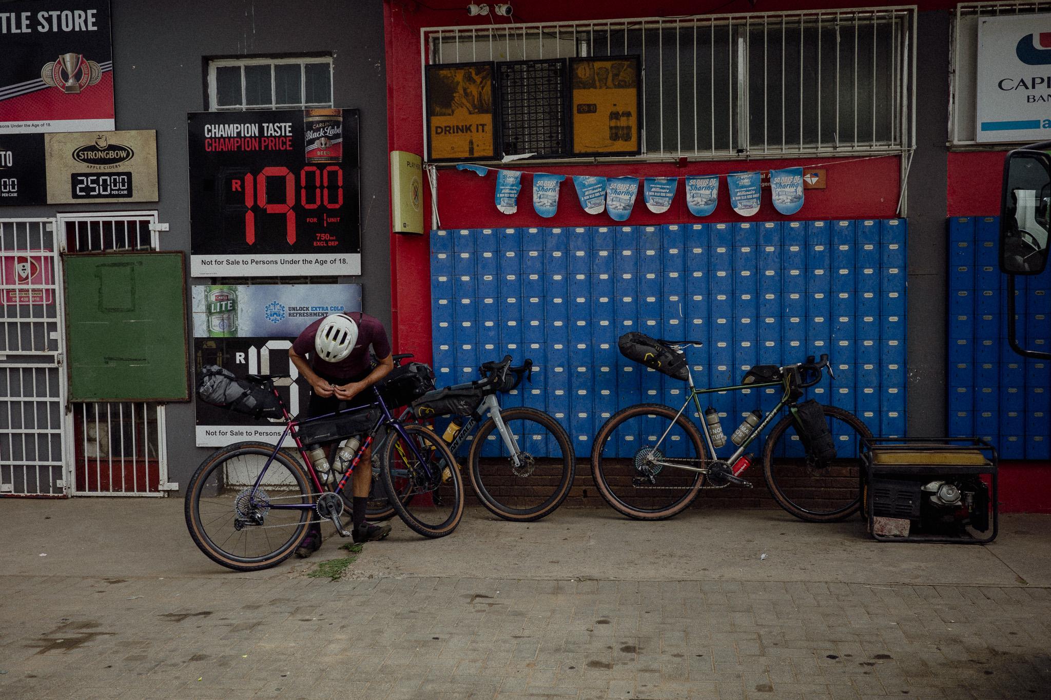 Cyclist with gravel bikes resting outside colorful store in Lesotho