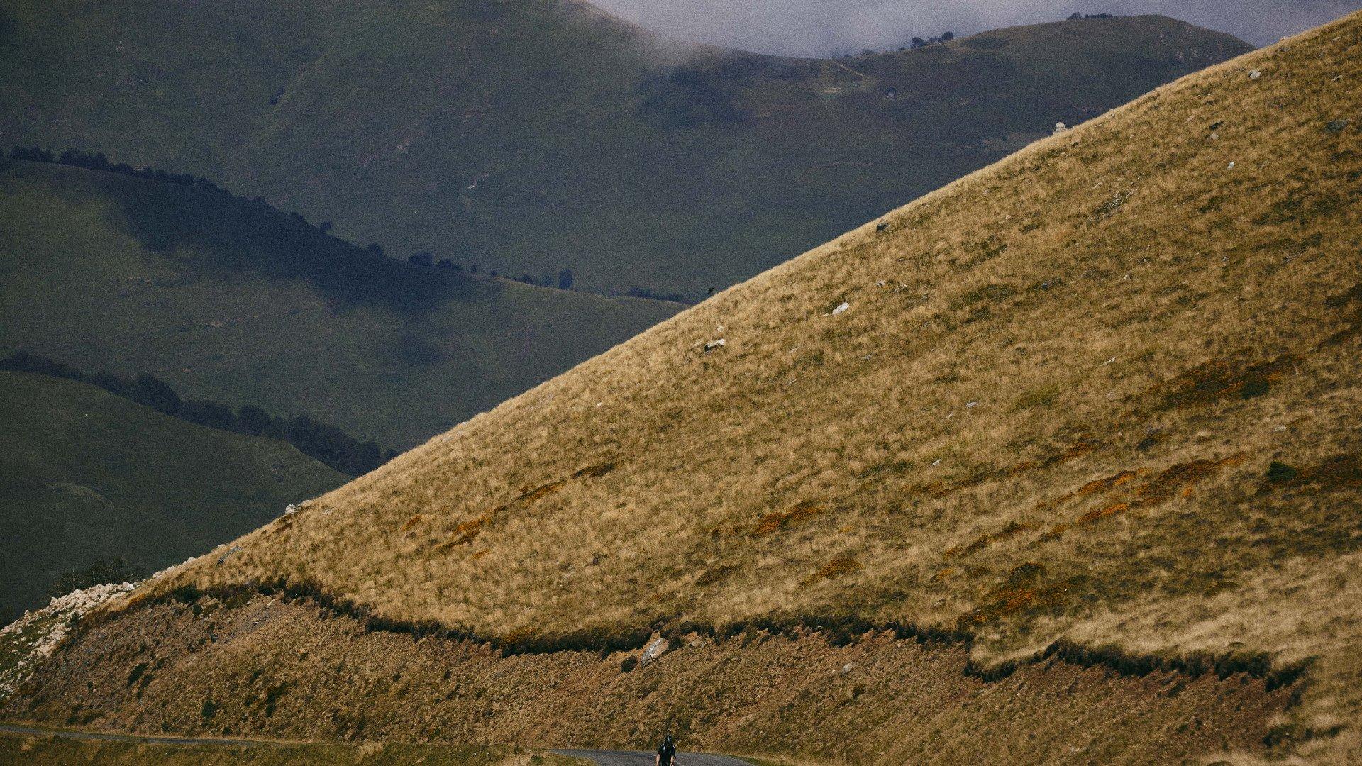 Rolling hills landscape with cyclist on remote mountain road