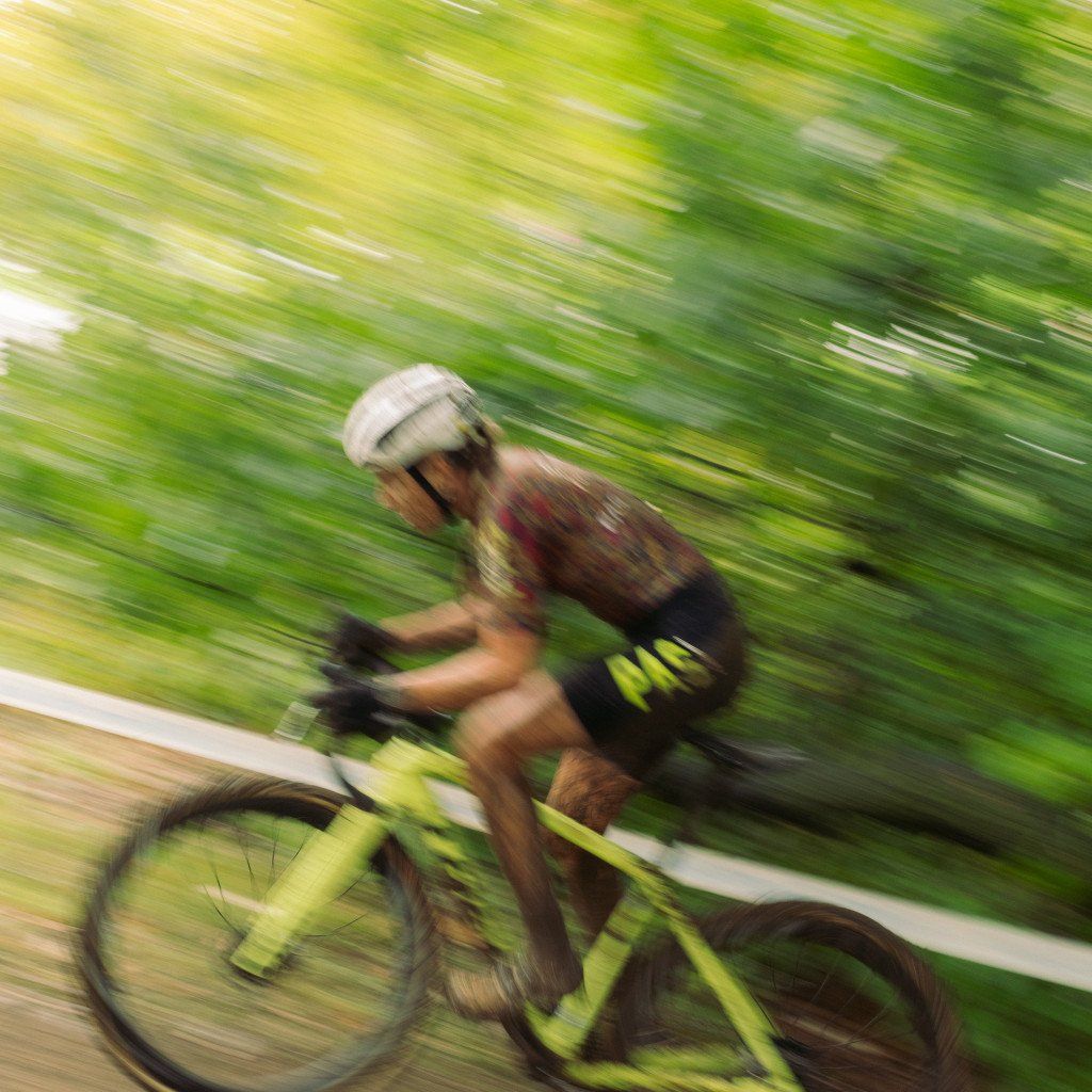 Cyclist in motion blur riding yellow bike through green countryside