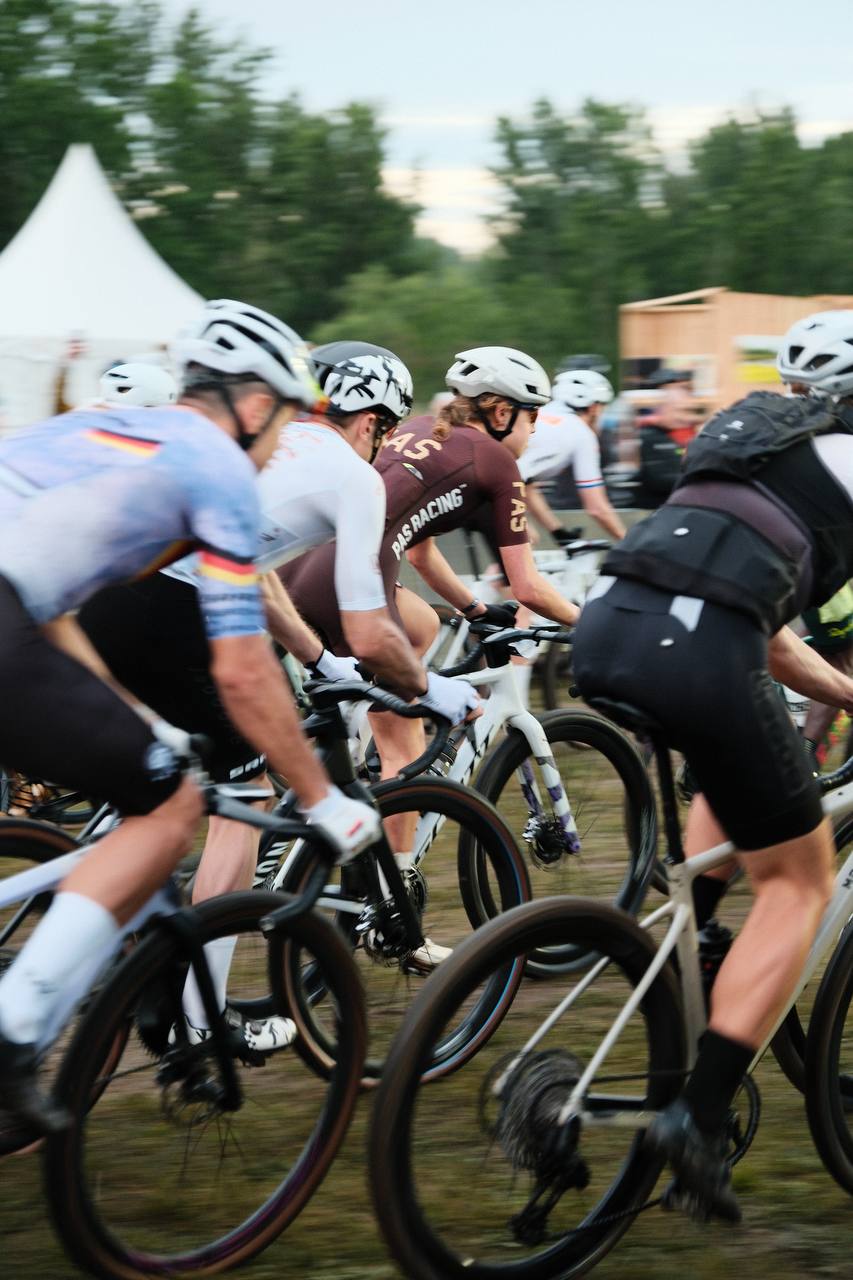 Cyclists in racing peloton wearing maroon and white jerseys during competitive event