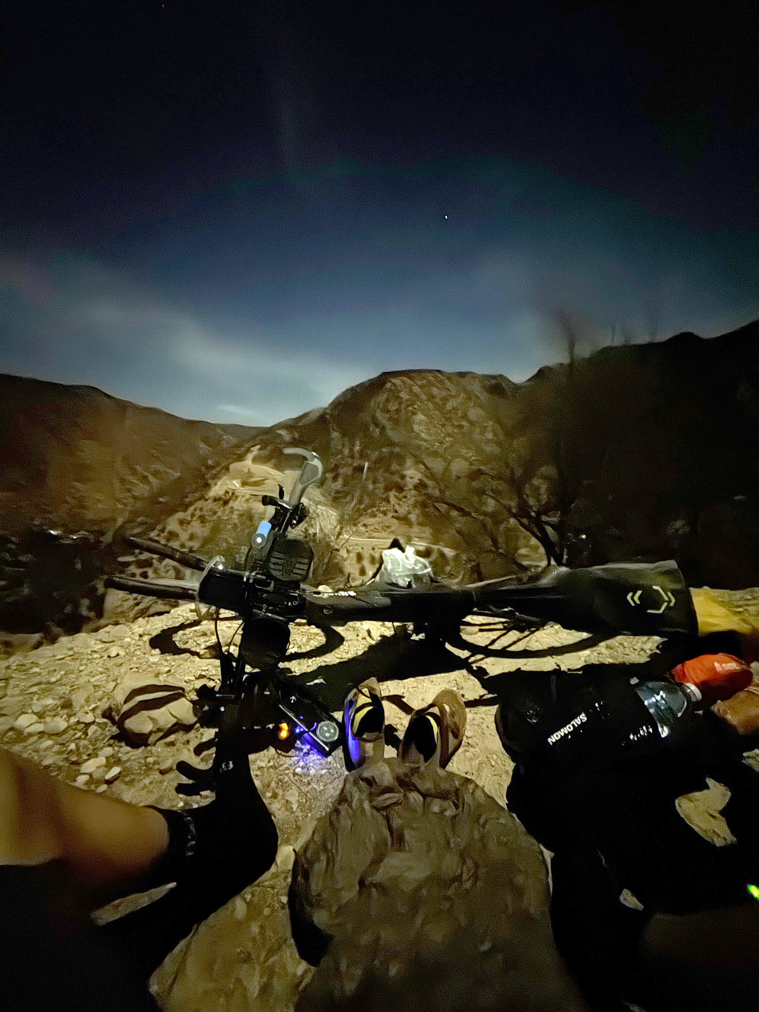 Gravel bike handlebars with lights against desert mountain landscape at twilight