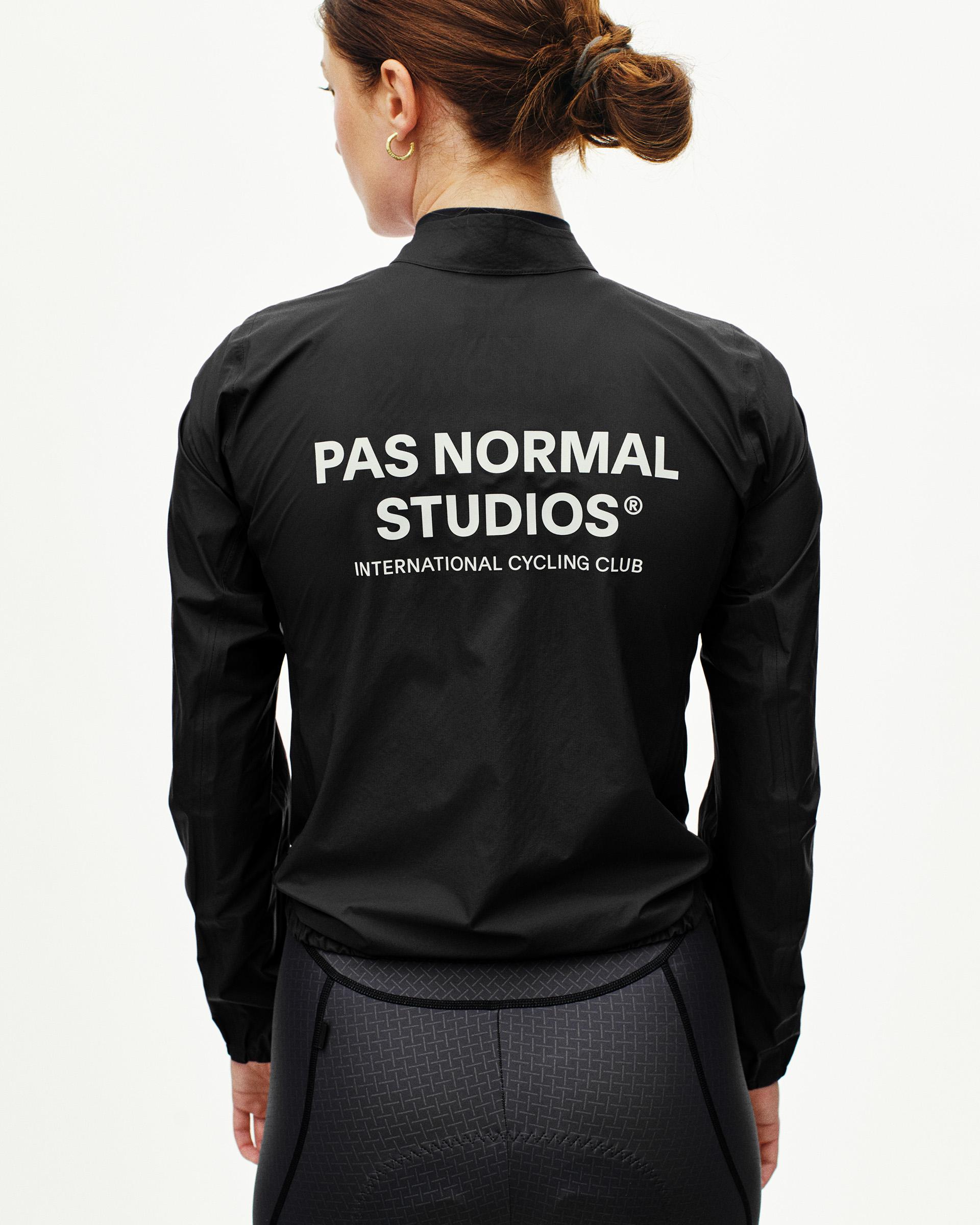 Black Mechanism cycling rain jacket on model, rear view with white back logo print