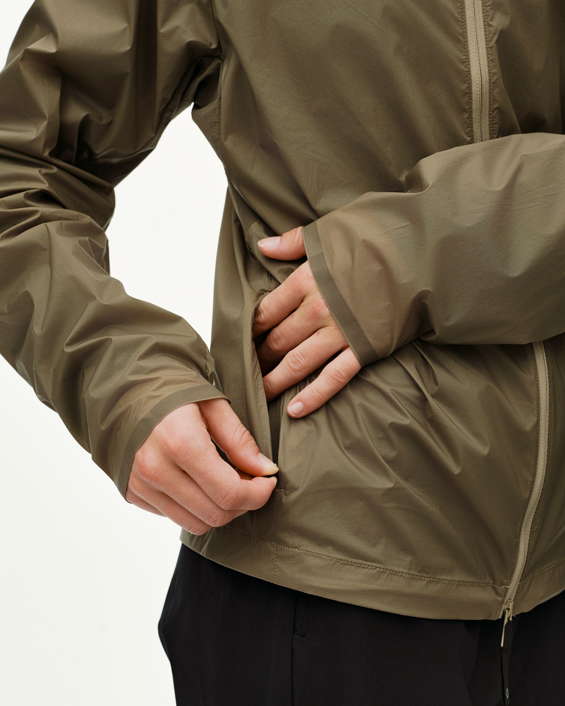 Dusty Earth khaki Balance Windproof cycling jacket, detail on model showing side zip pocket and ribbed cuff