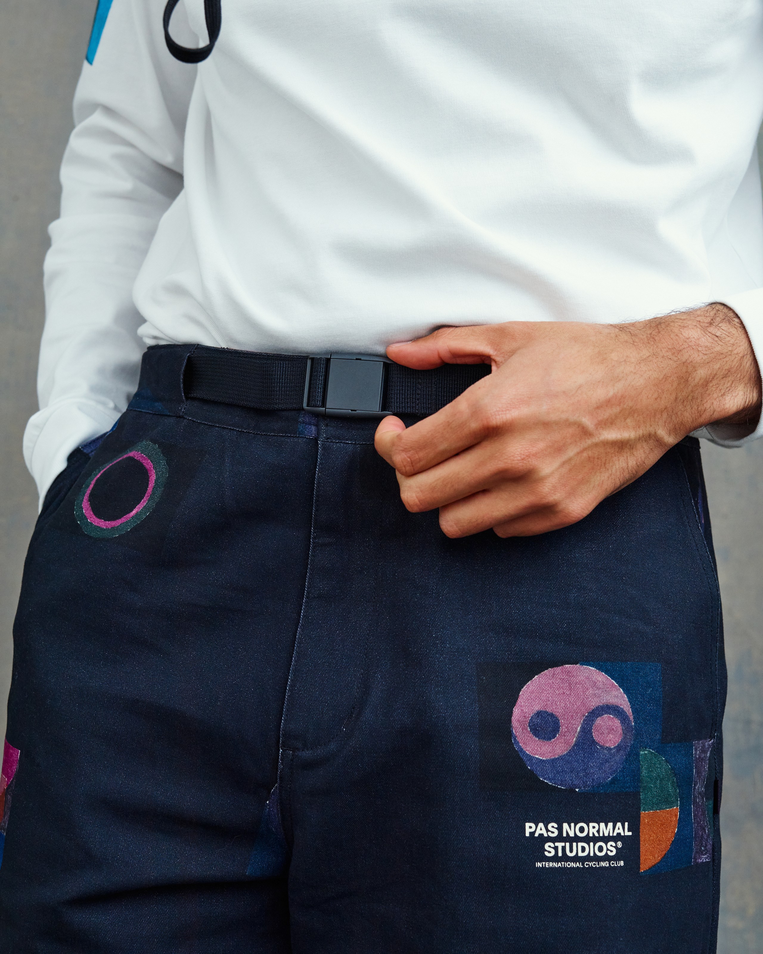 Canvas waist belt with black locking buckle on navy twill pants for on-the-go adjustment