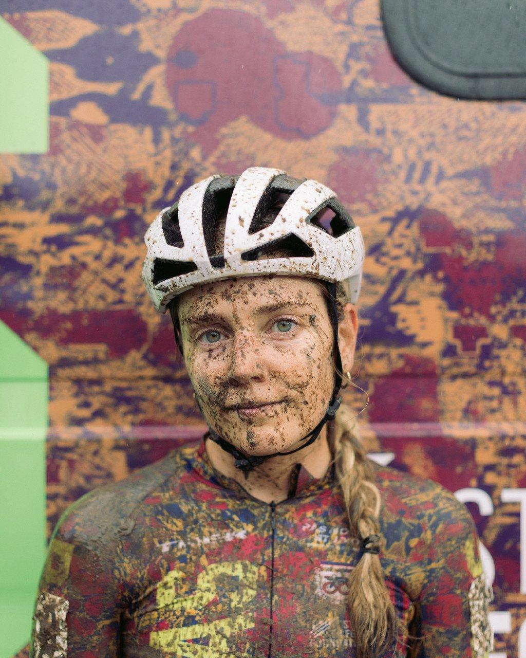 Model wearing muddy cycling kit and white helmet after off-road race