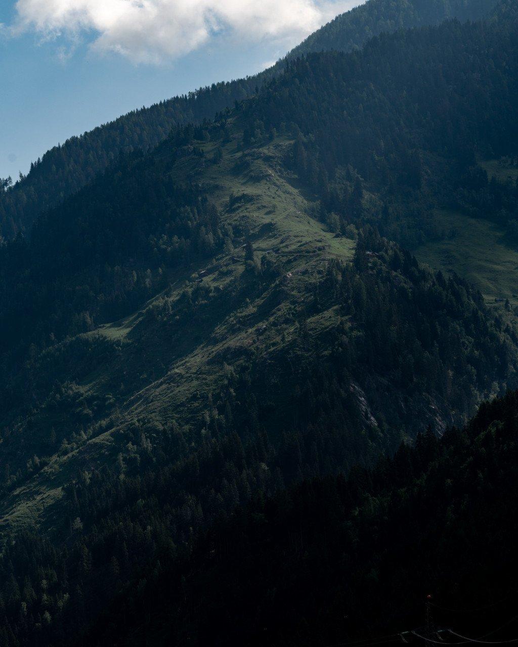 Mountainous landscape with forested slopes under cloudy sky