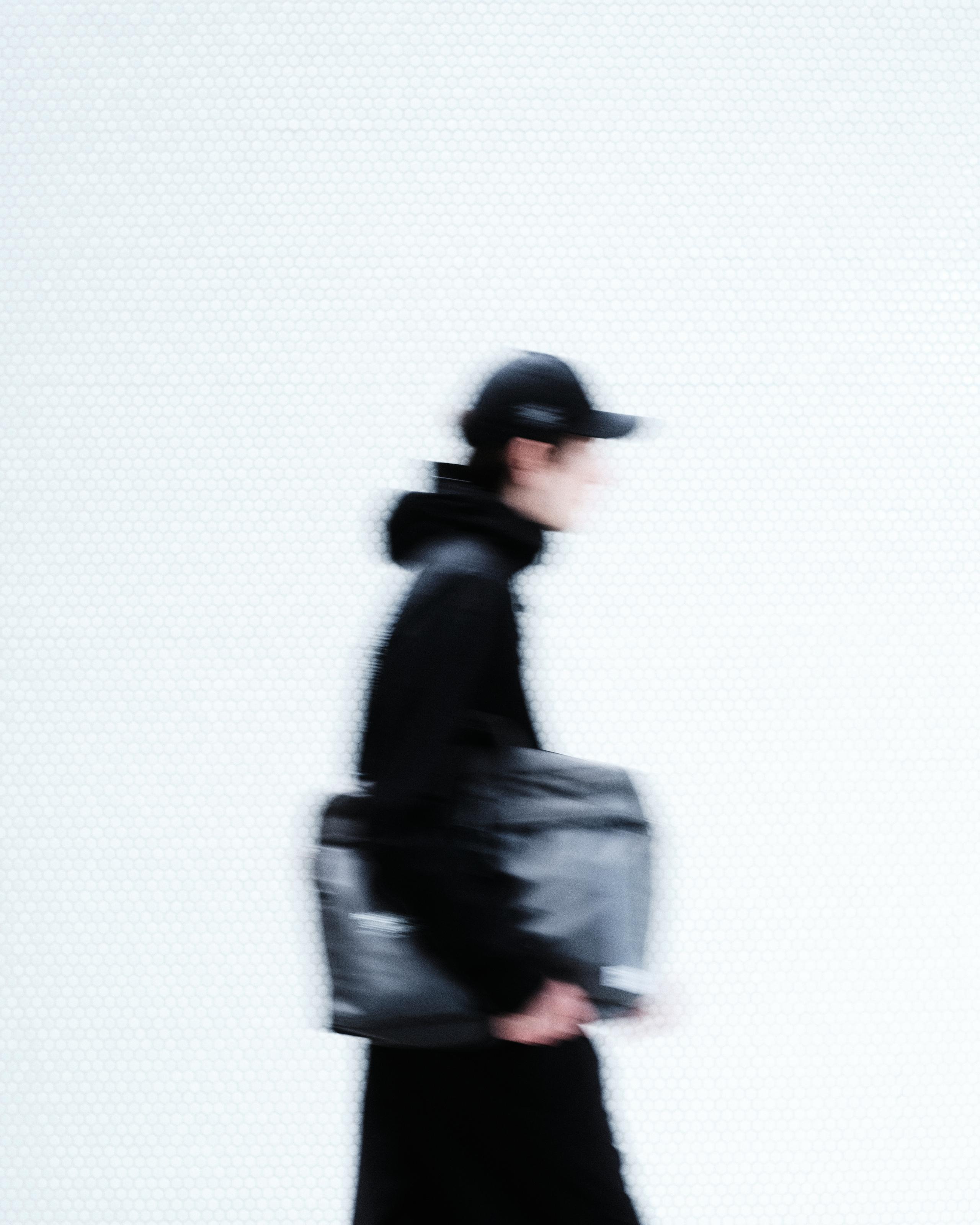 Model in motion blur wearing black cycling apparel and carrying dark messenger bag