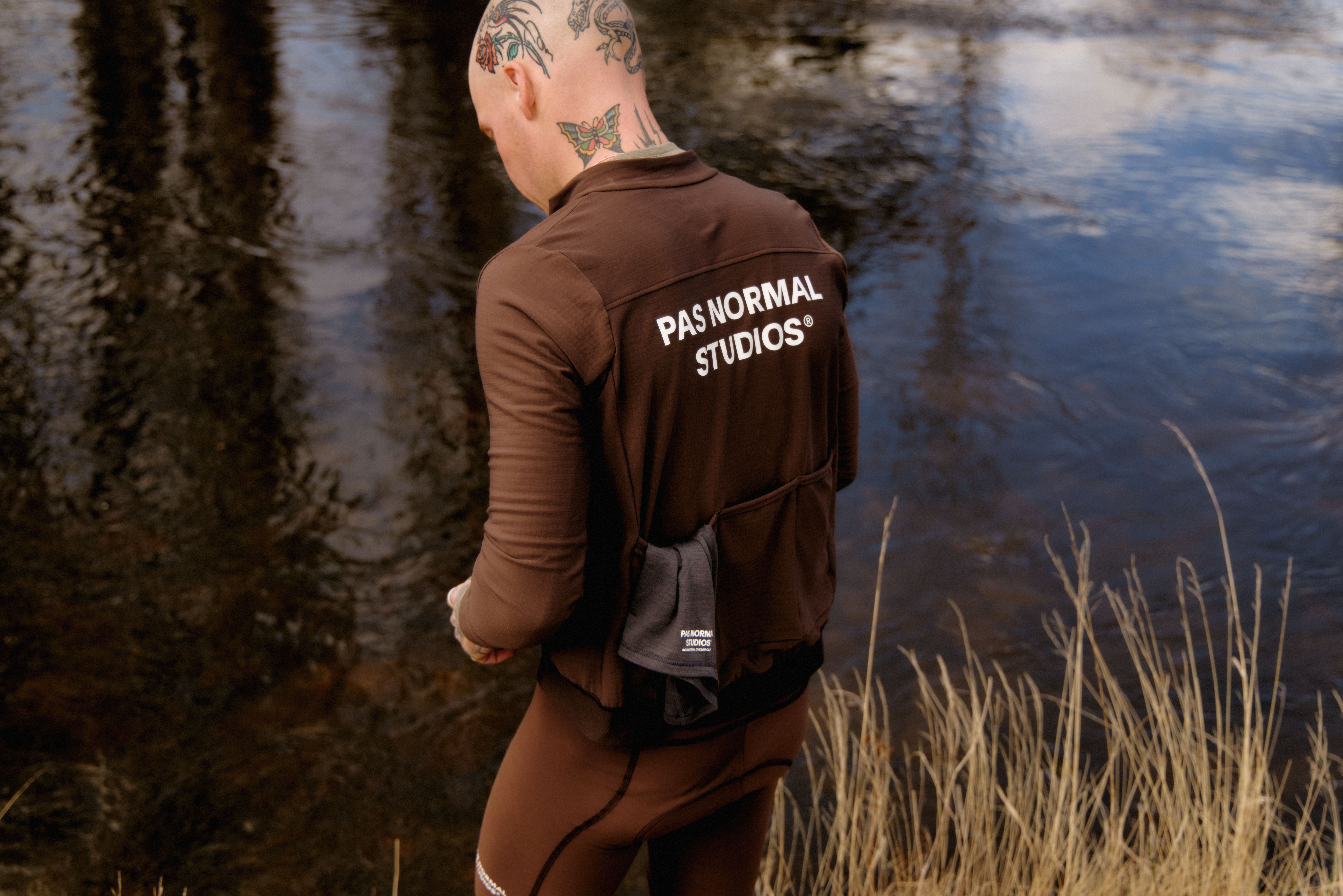 Model wearing brown long sleeve jersey with back branding by water