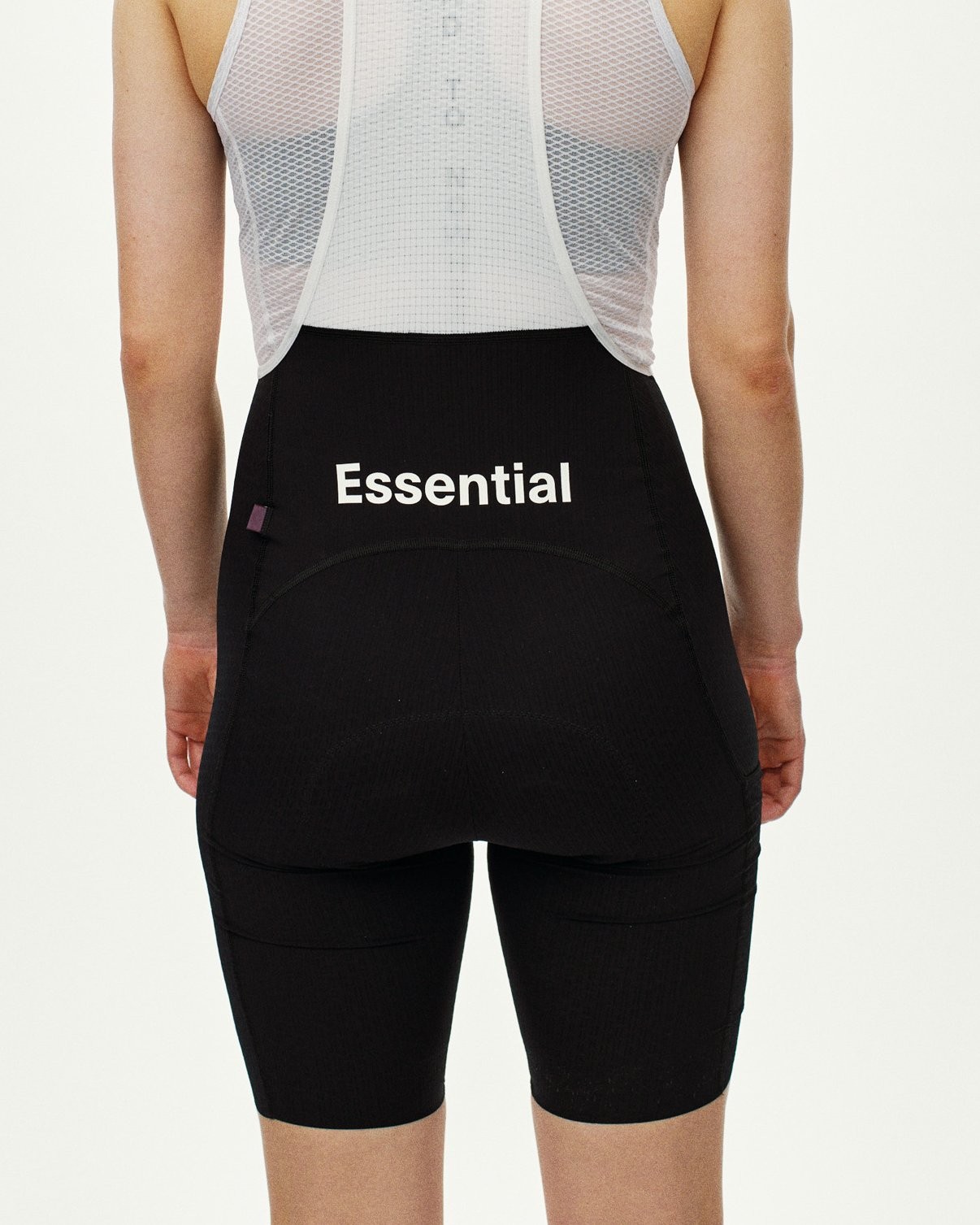 Black Essential cycling bibs on model, rear view with white Essential logo print