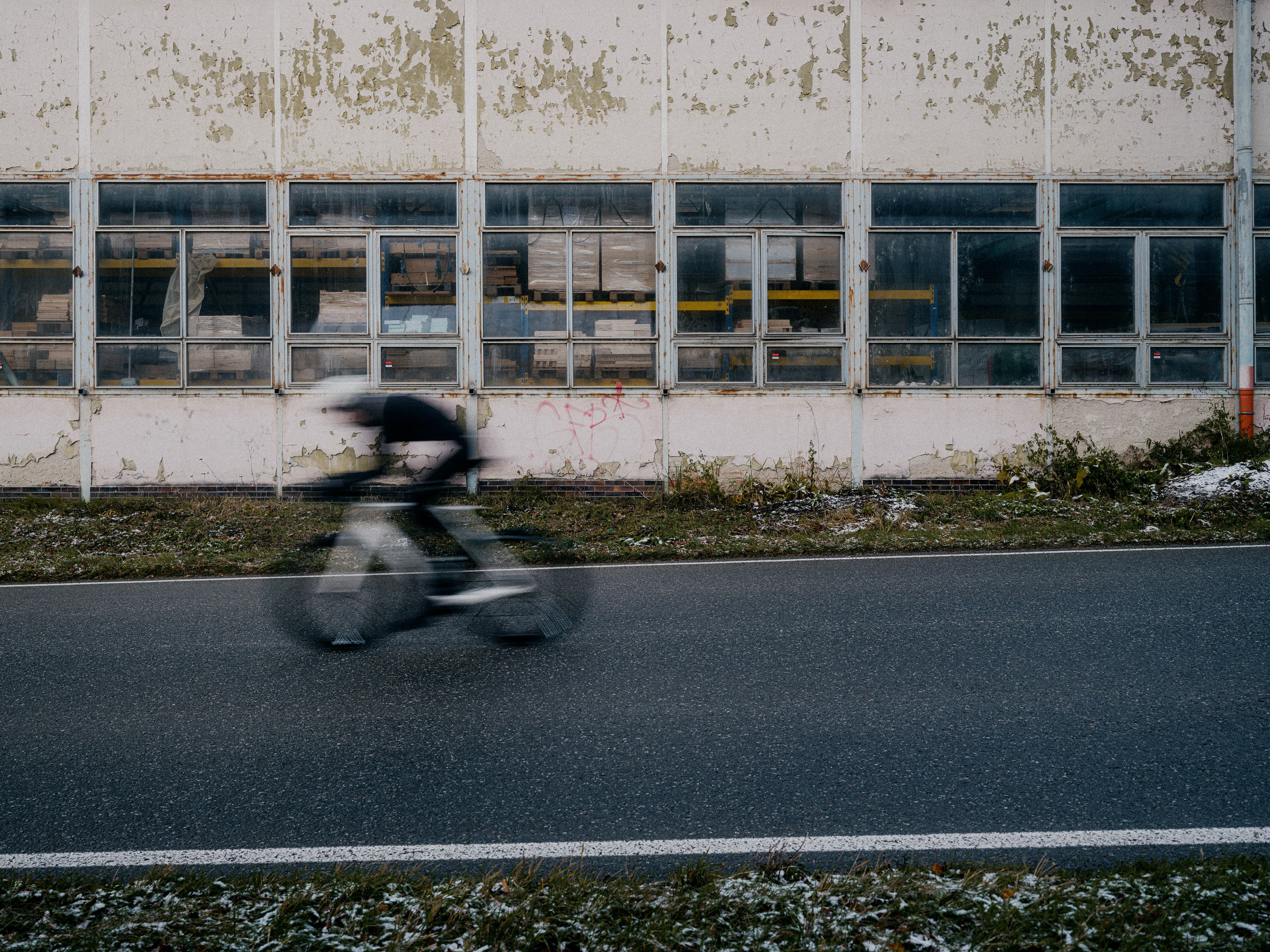 Cyclist in motion blur riding past industrial building with weathered windows