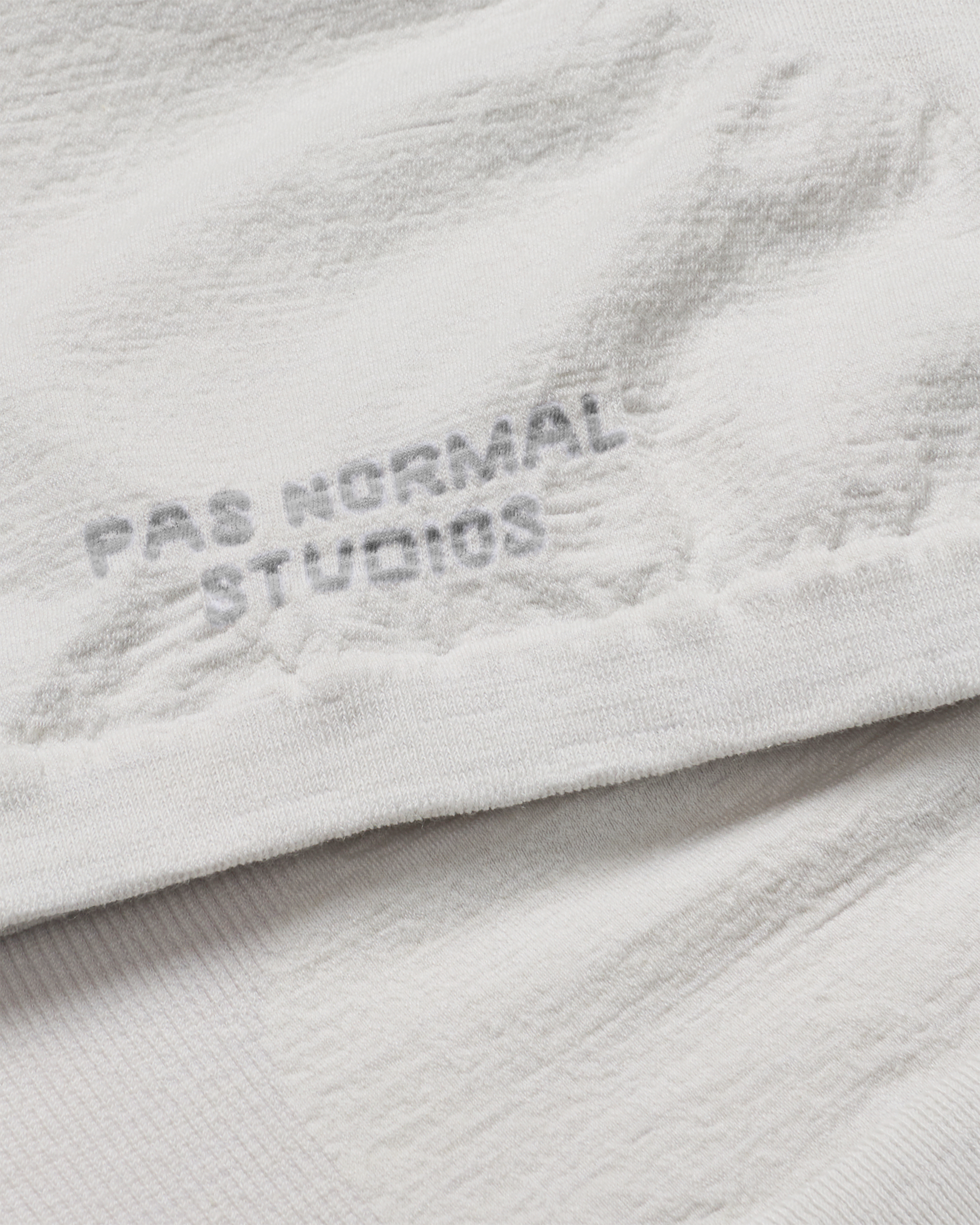 Misty Grey Logo Merino Knit necktube, close-up detail showing tonal logo print on textured knit fabric