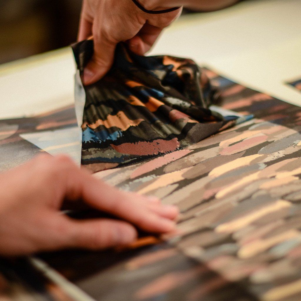 Hands examining multicolored fabric samples with abstract patterns during design process
