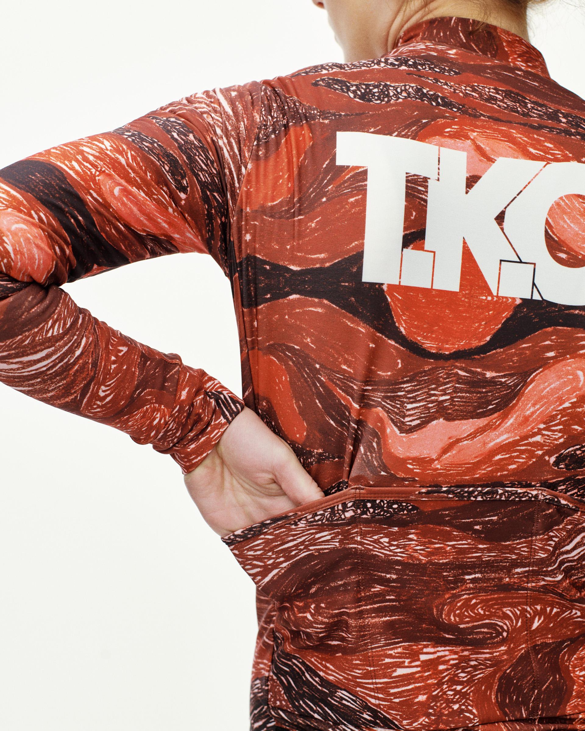 Red T.K.O. Mechanism long sleeve cycling jersey on model, rear view with all-over swirl print and white back logo