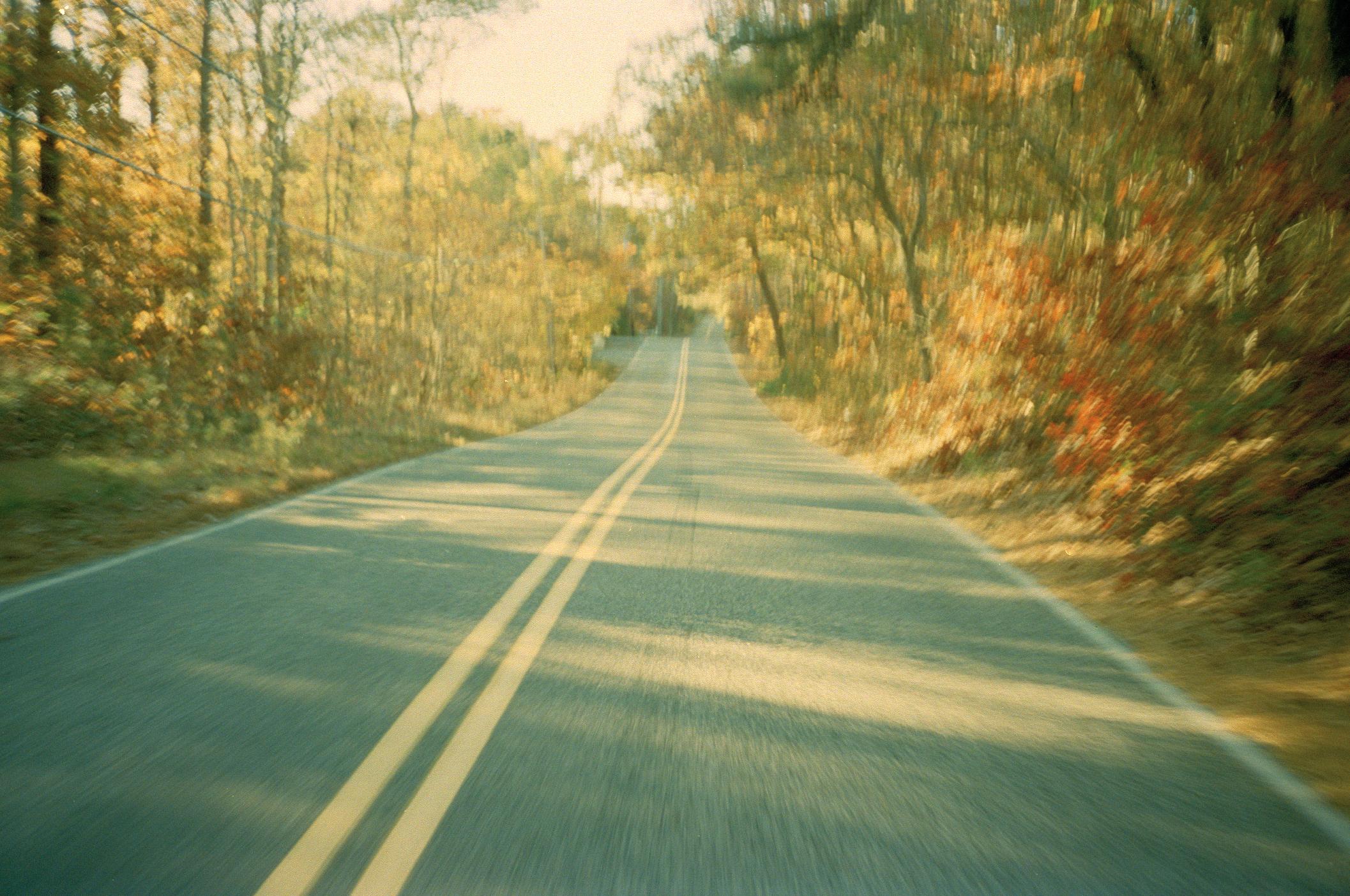 Empty road through autumn forest with motion blur and golden light