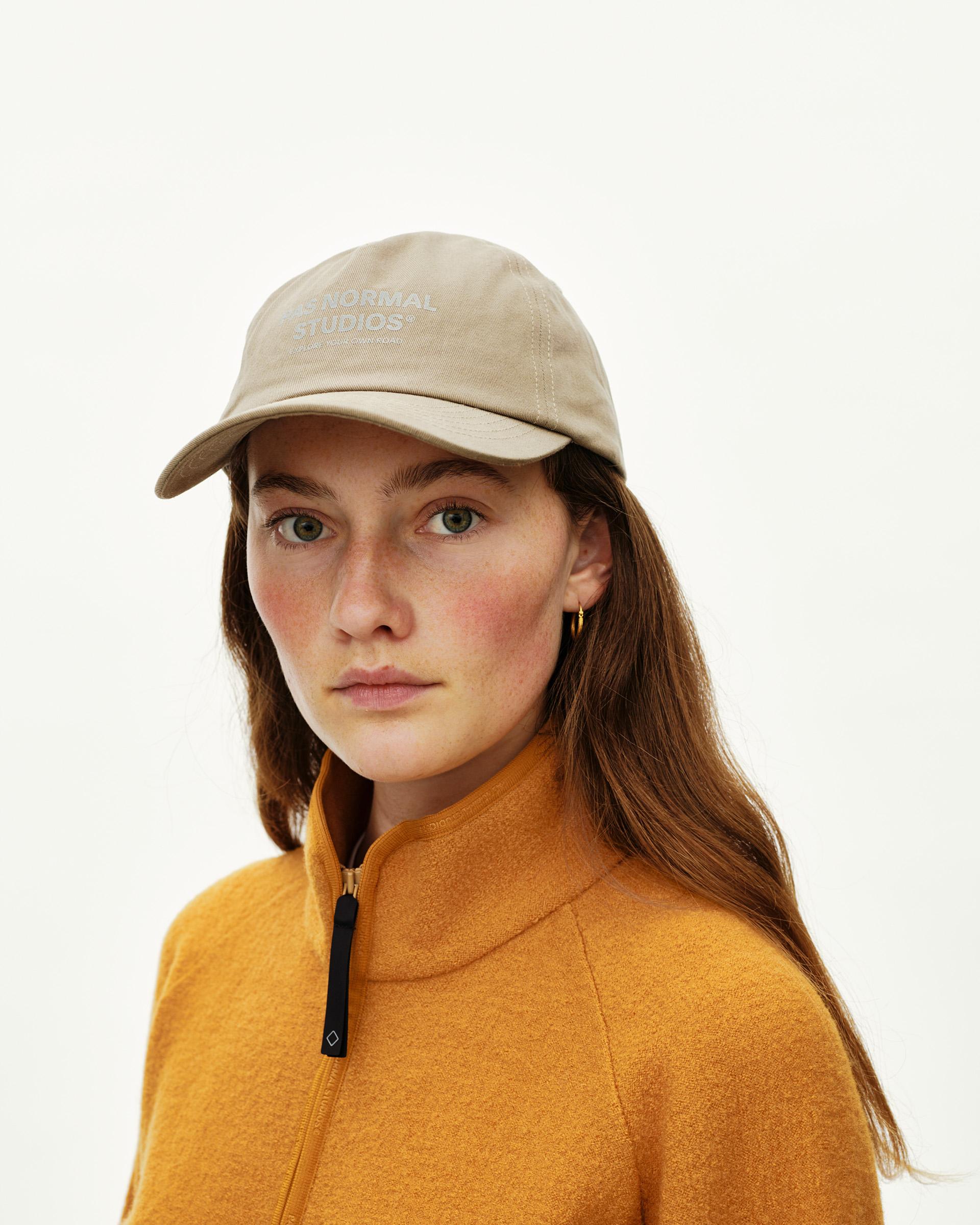 Dusty Earth khaki Off-Race Cotton cap on model, front view with tonal logo print on crown