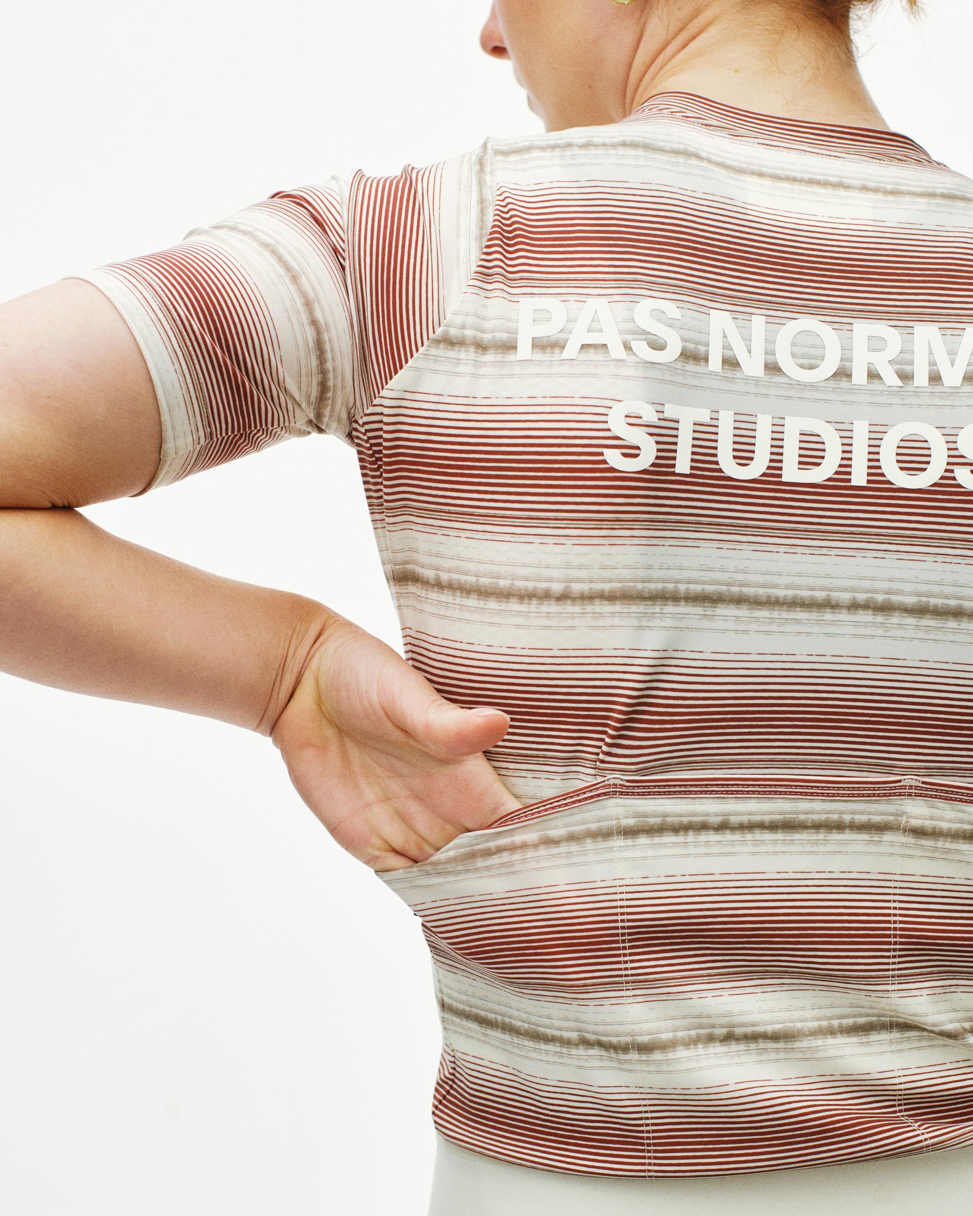 White Essential cycling jersey on model, rear view with red and beige horizontal stripes