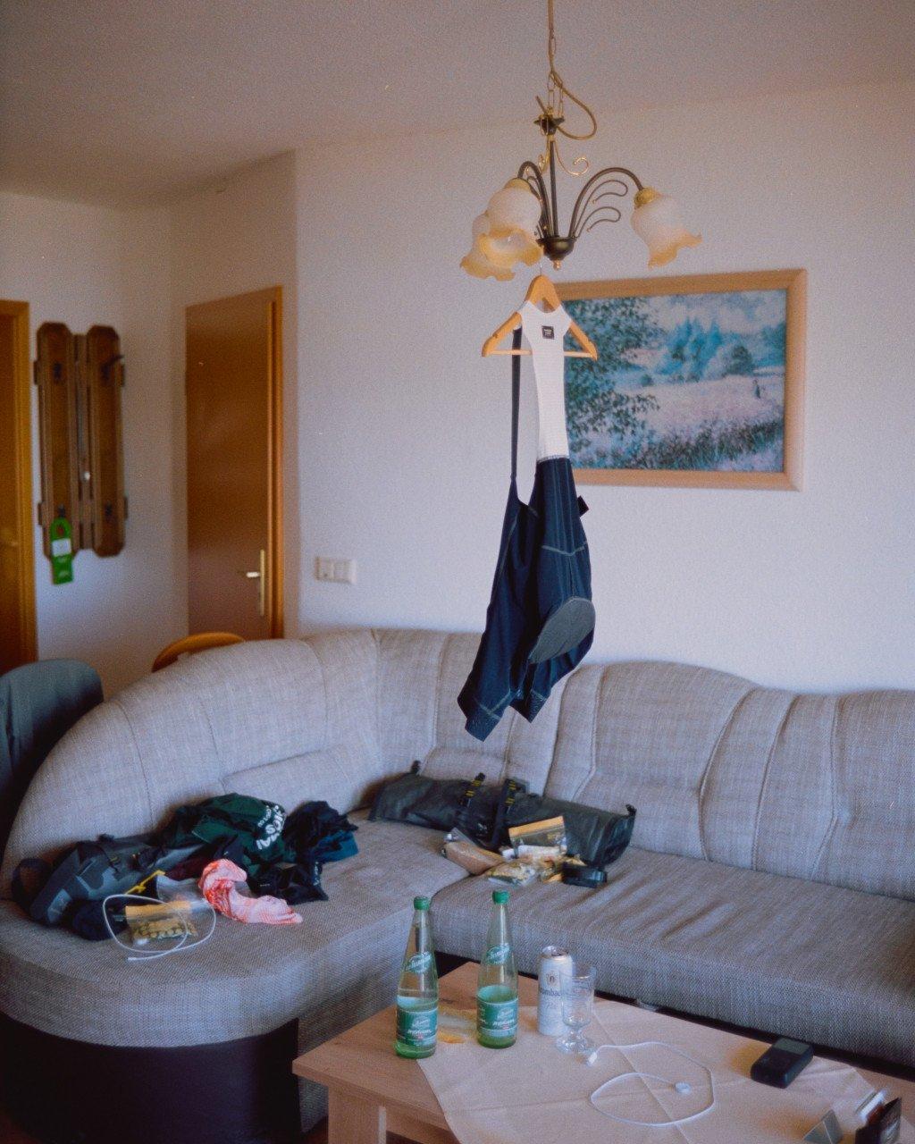 Cycling apparel hanging on wooden hanger in home interior with navy shorts and white jersey