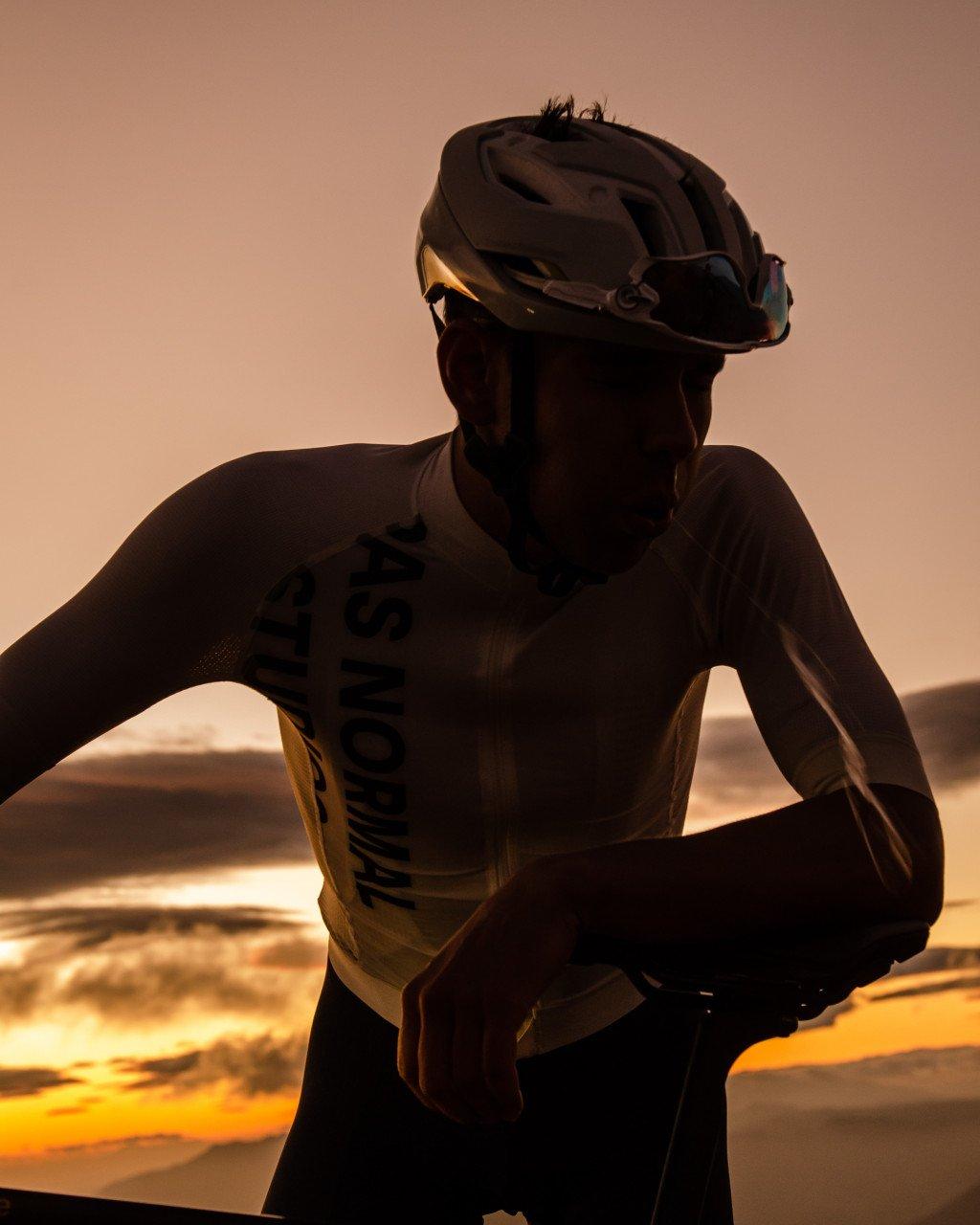 Model wearing cycling helmet and jersey with geometric chest pattern during golden hour sunset