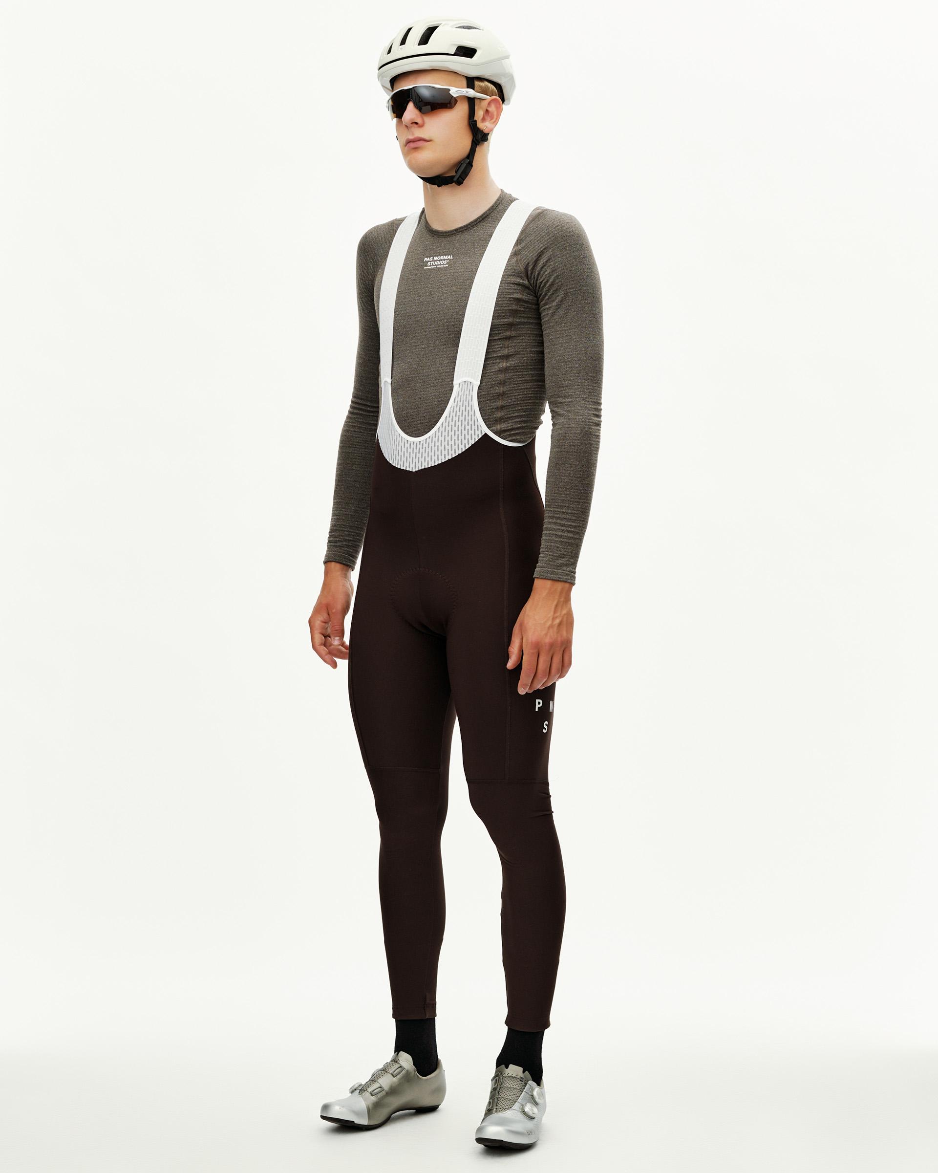 Dark Coffee Mechanism men's thermal cycling bib tights on model, three-quarter front view with white mesh bib straps