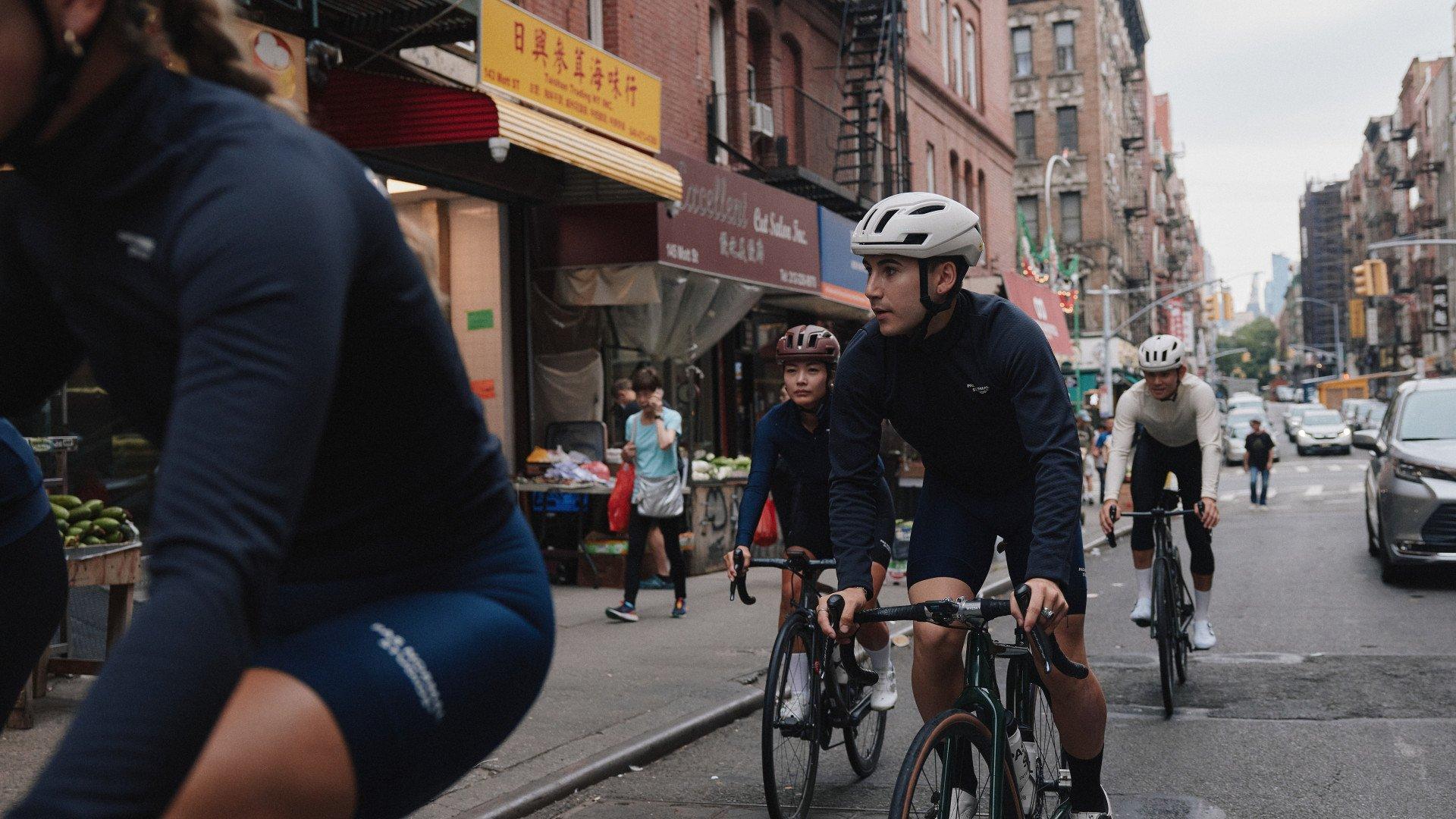 Models wearing navy cycling apparel riding through New York City streets