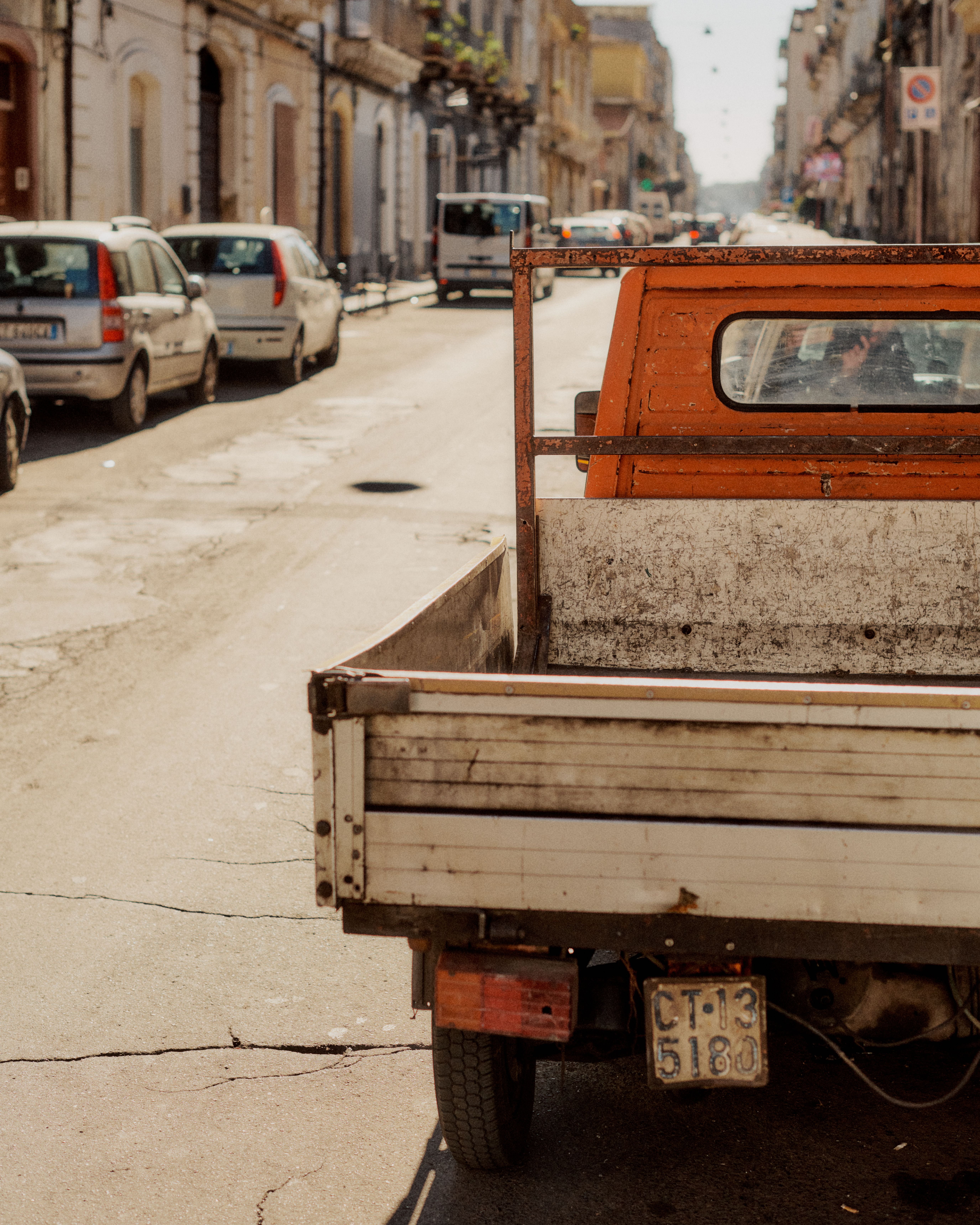 Vintage orange and white truck parked on Italian street with historic buildings