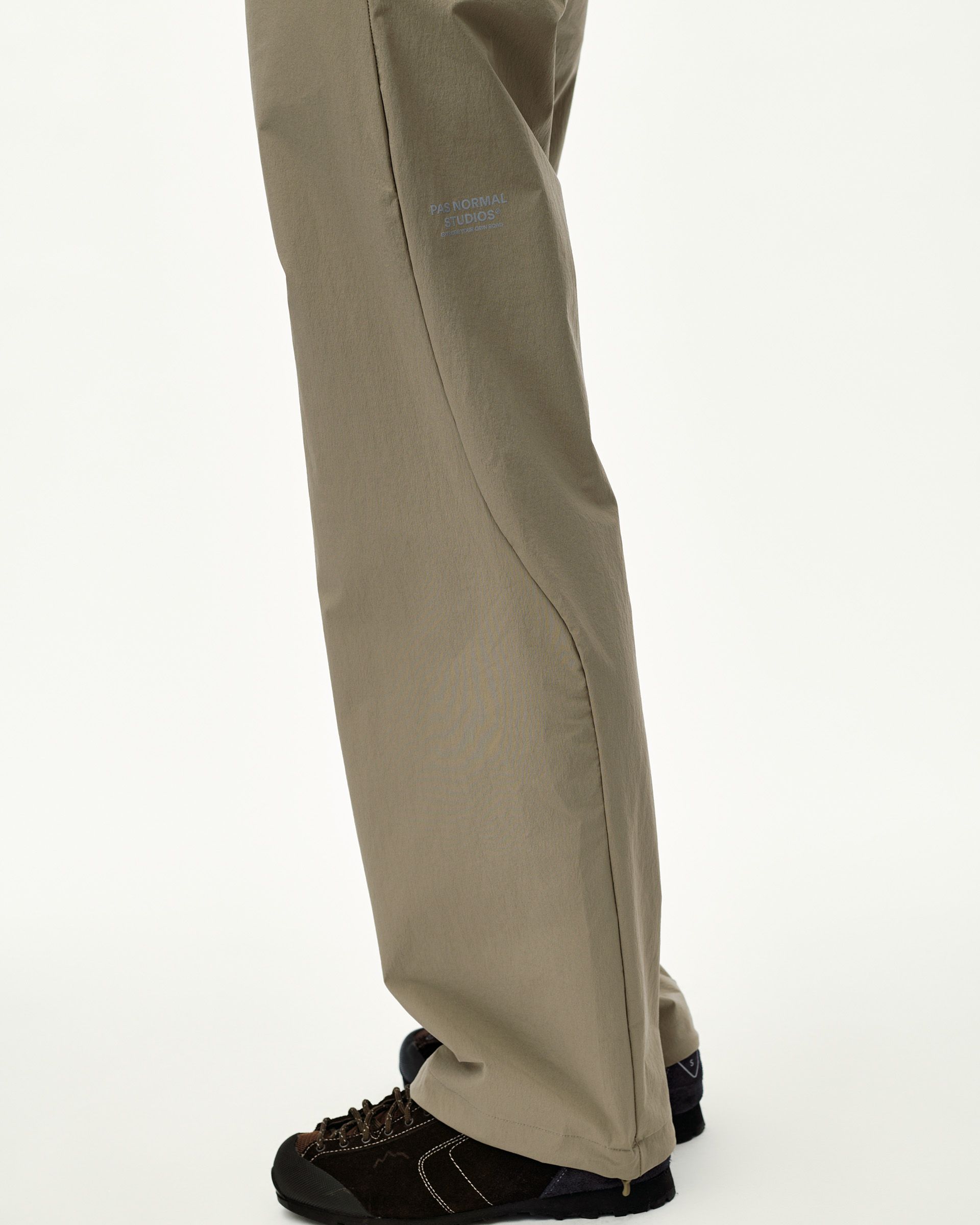 Dusty Earth khaki Off-Race Tech pants on model, side view with tonal logo print on thigh
