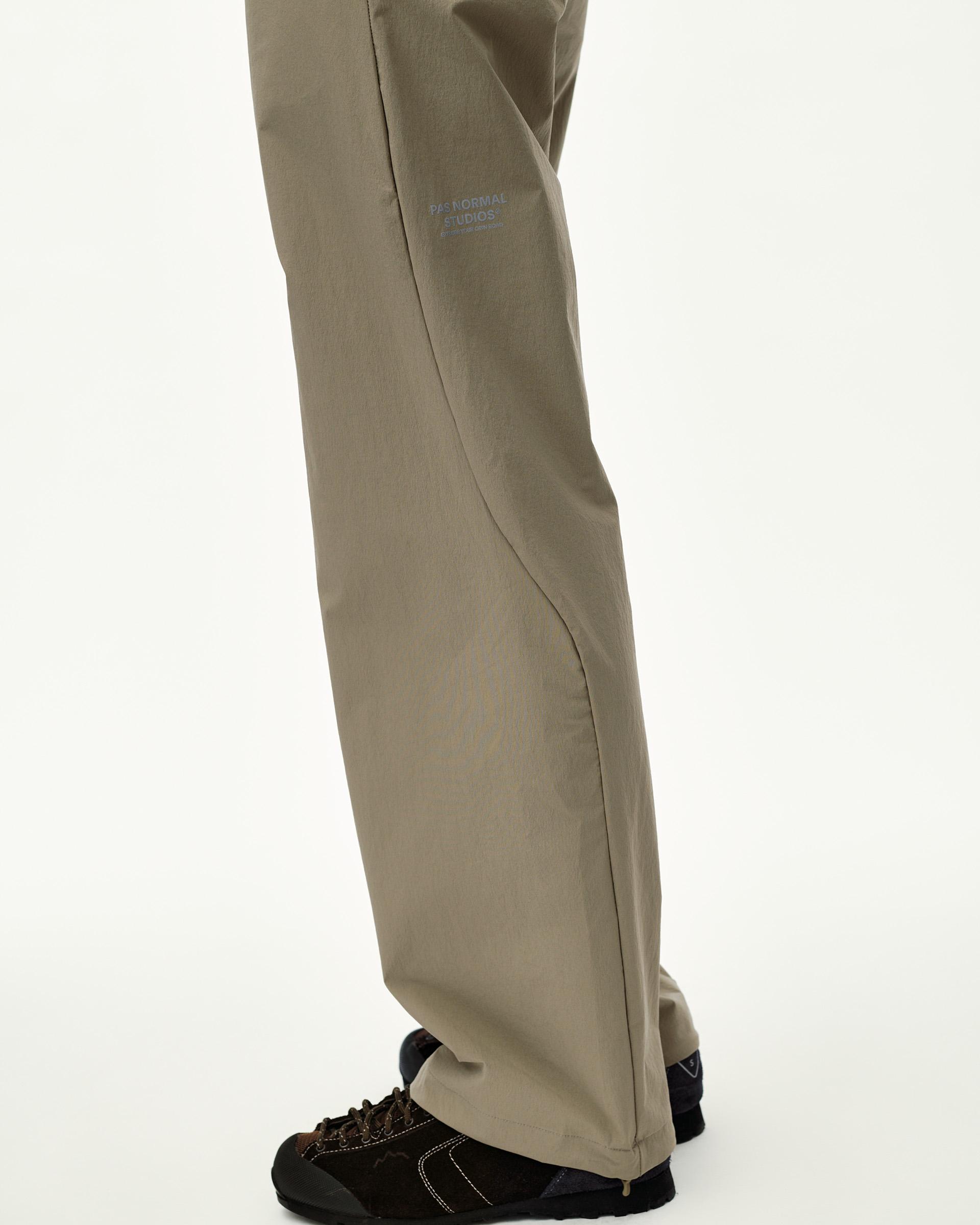 Dusty Earth khaki Off-Race Tech pants on model, side view with tonal logo print on thigh