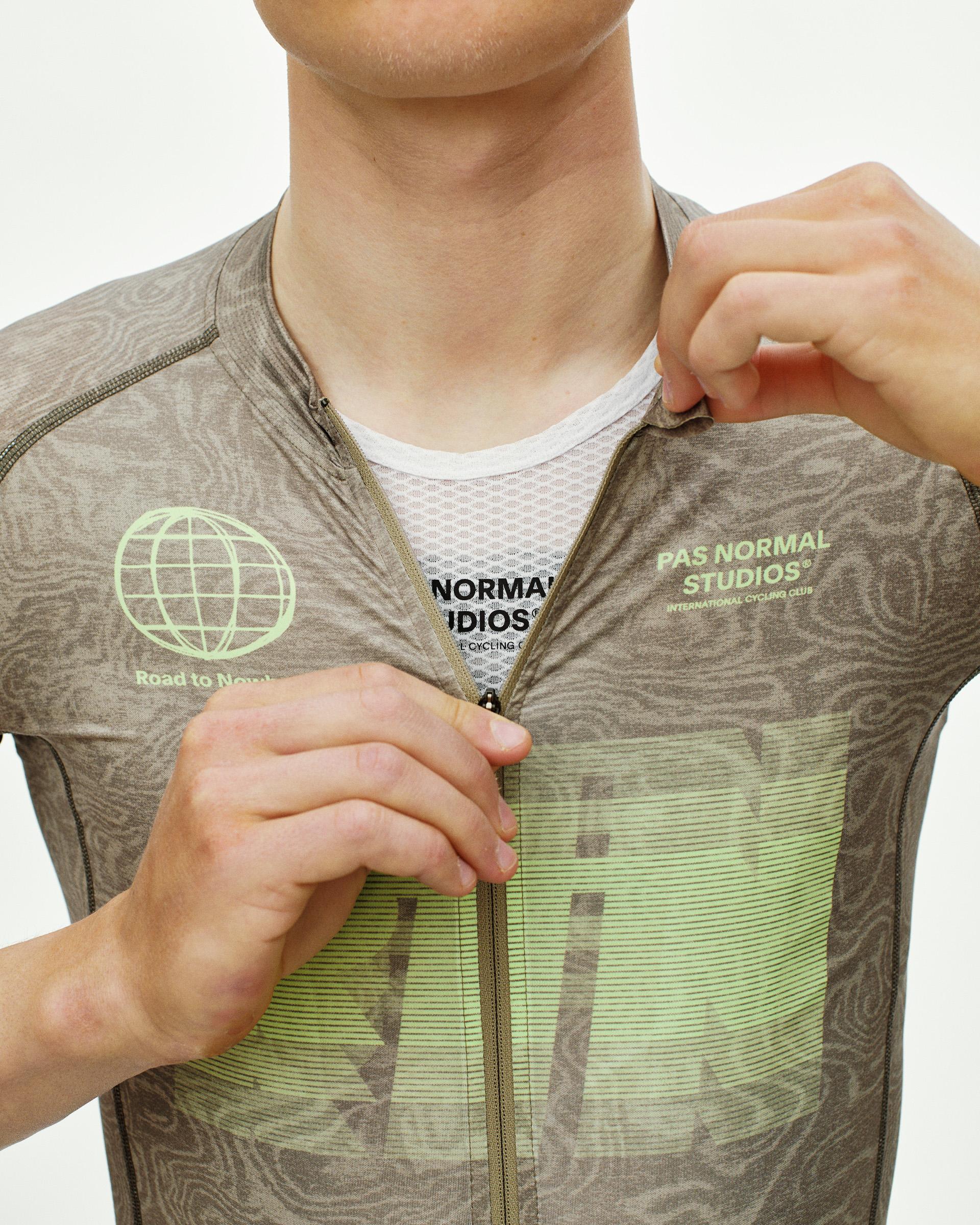 Brown Mechanism Logo cycling jersey on model, front detail view with green globe graphic and tonal woodgrain pattern