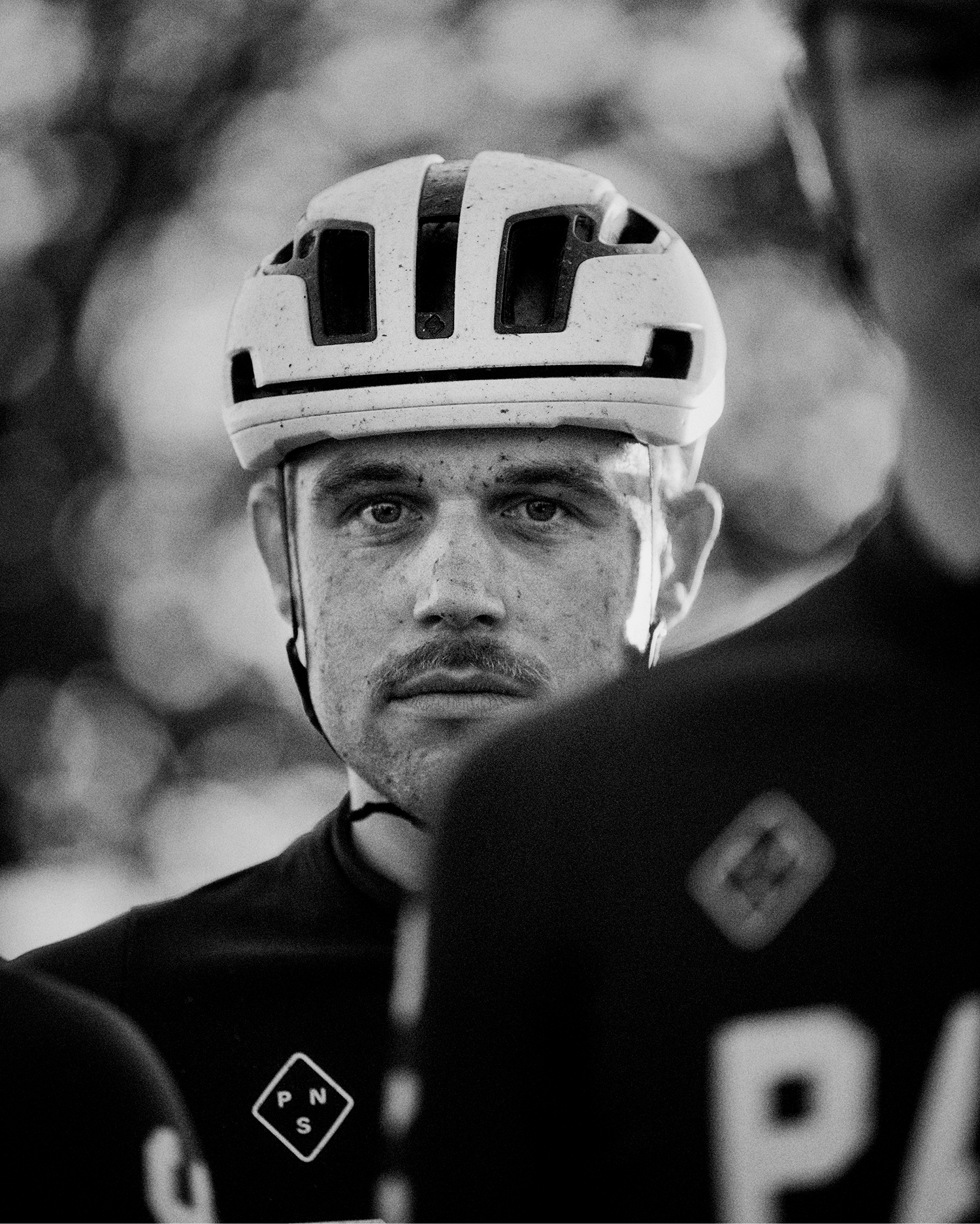 Model wearing white cycling helmet and black jersey with logo in black and white portrait