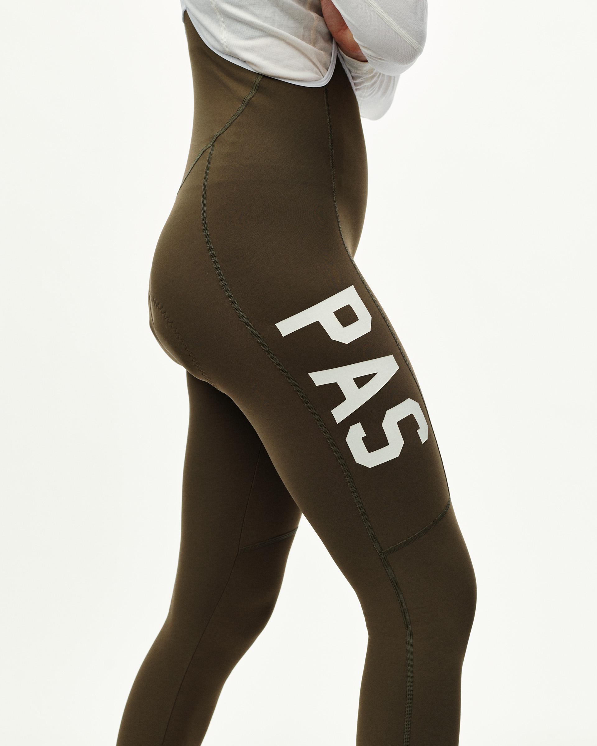 Dark Earth khaki PAS Mechanism Thermal Long cycling bibs on model, side view with white PAS leg print