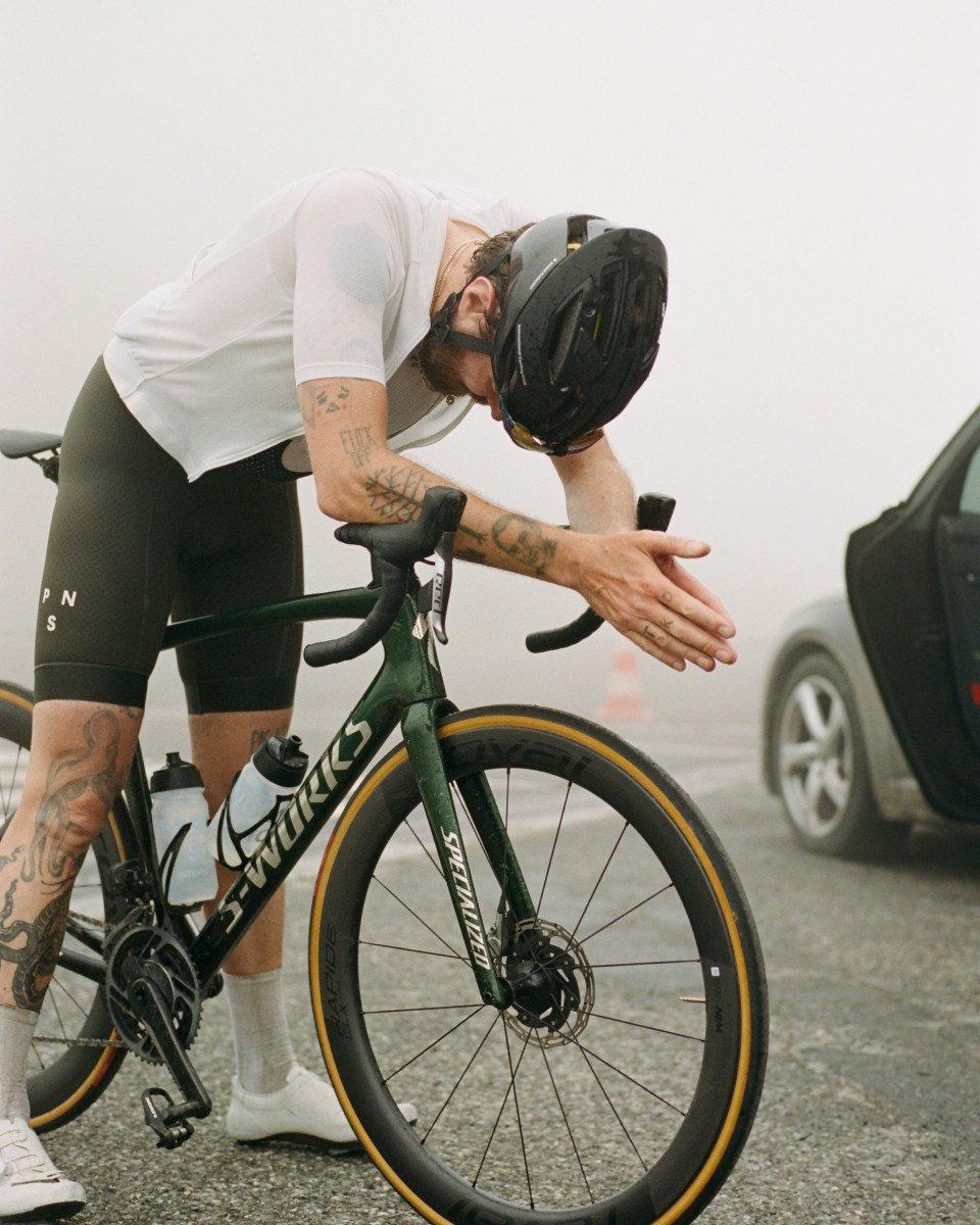 Model wearing white cycling jersey and black shorts with aero helmet on time trial bike