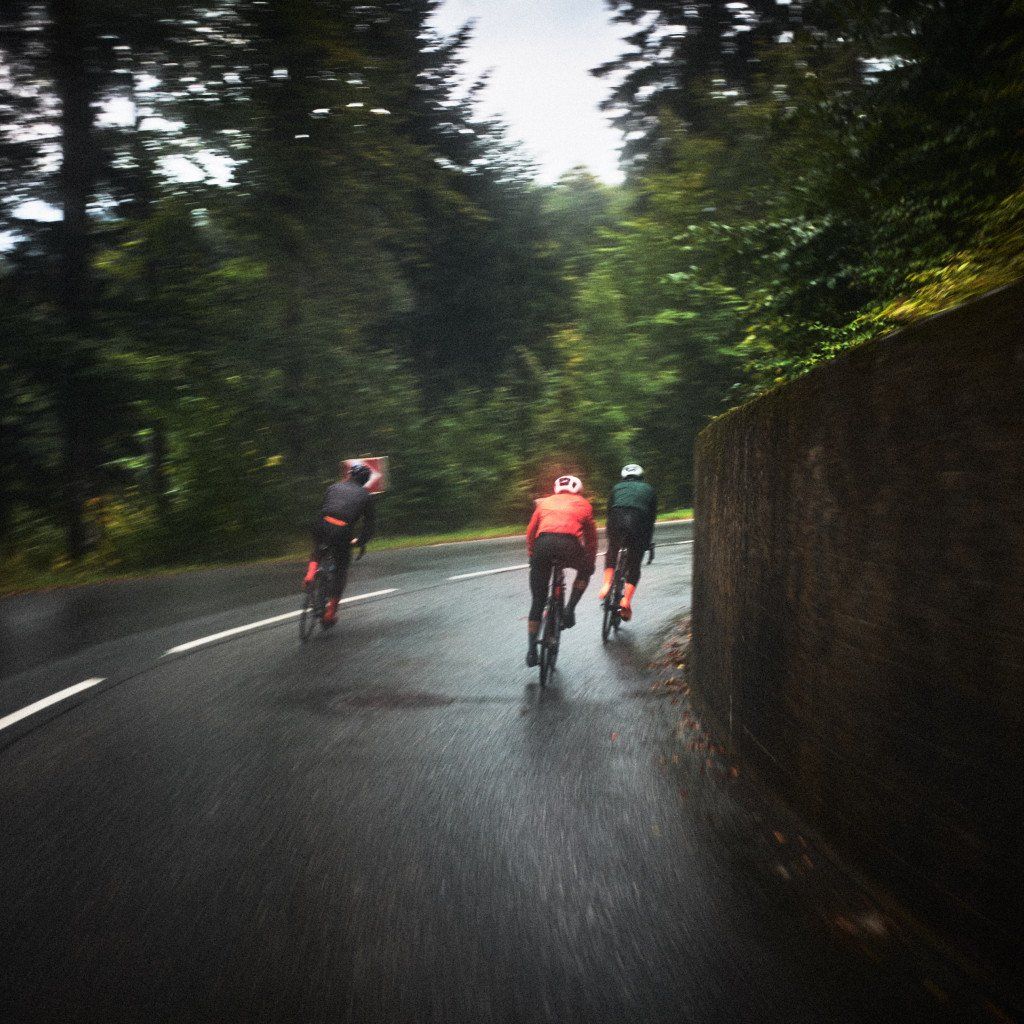 Three cyclists riding on wet forest road with motion blur effect