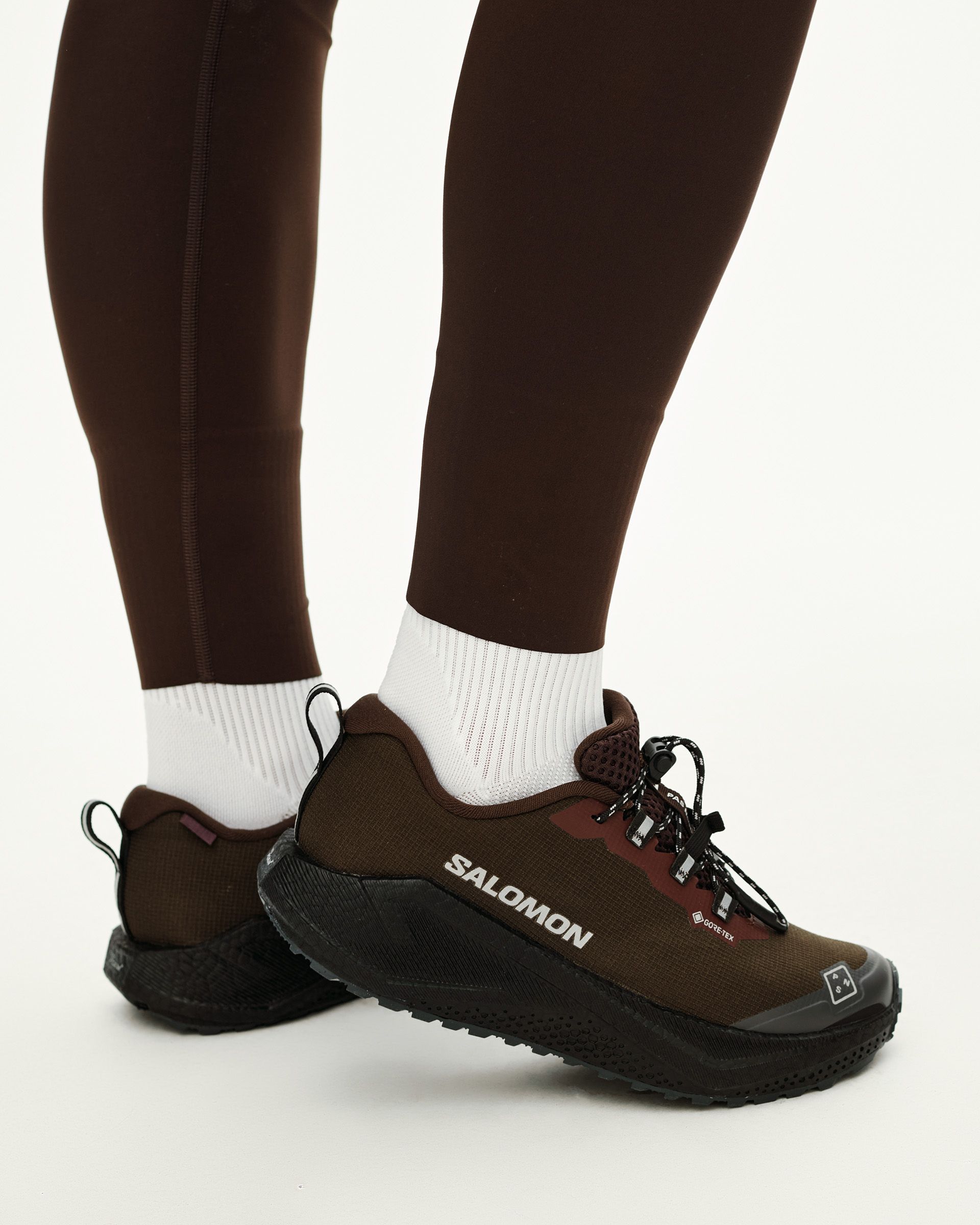 Light Brown Salomon AERO BLAZE 4 GRVL GTX trail shoes on model, side view with black sole and lace-up front