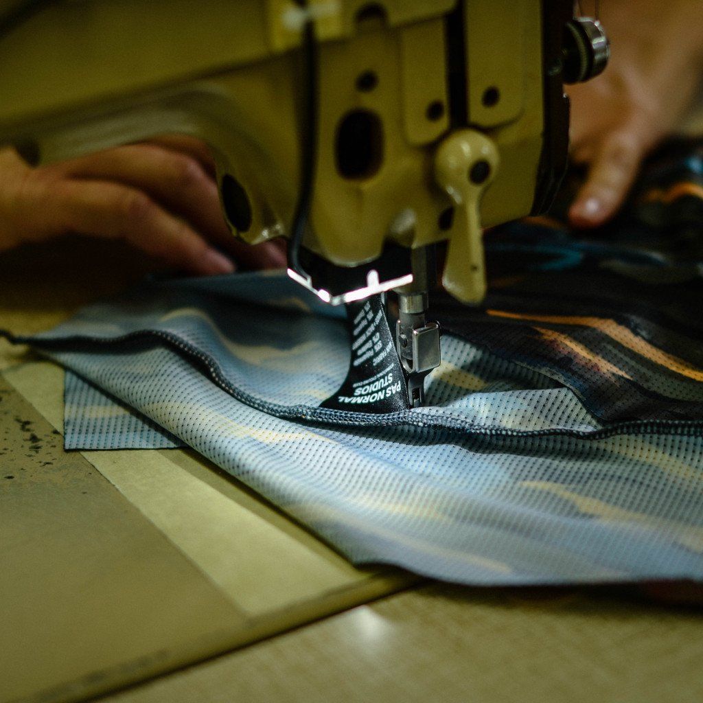 Sewing machine stitching blue cycling jersey with reflective details in manufacturing process