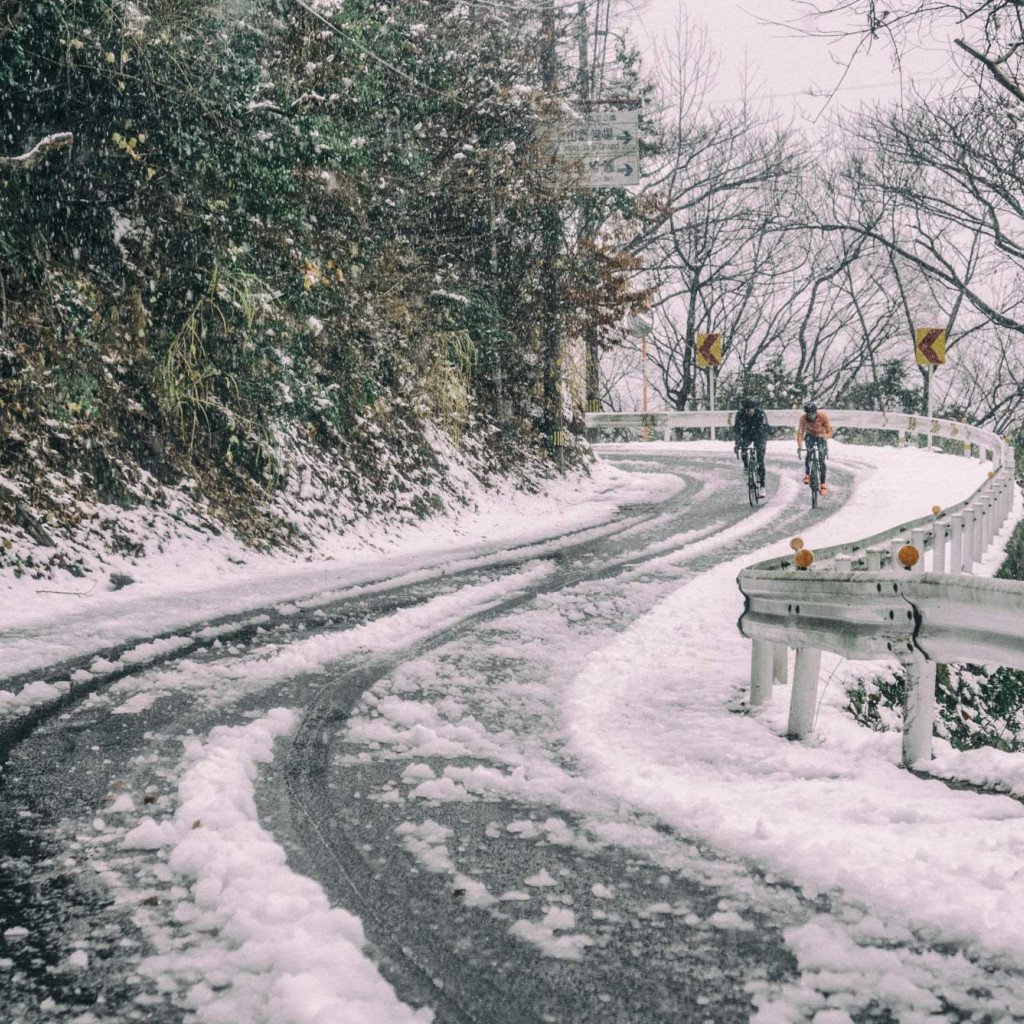 Two cyclists riding on snowy mountain road in Japan