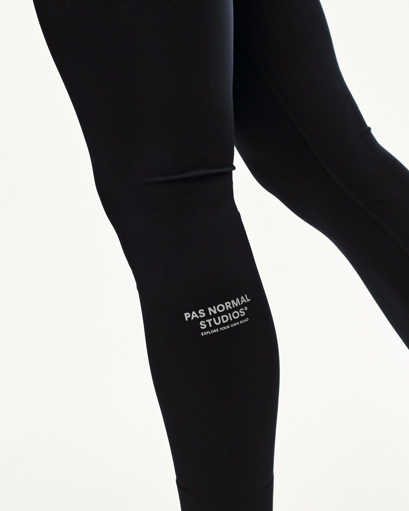 Black Balance long tights, detail view on model showing lower leg with small logo print
