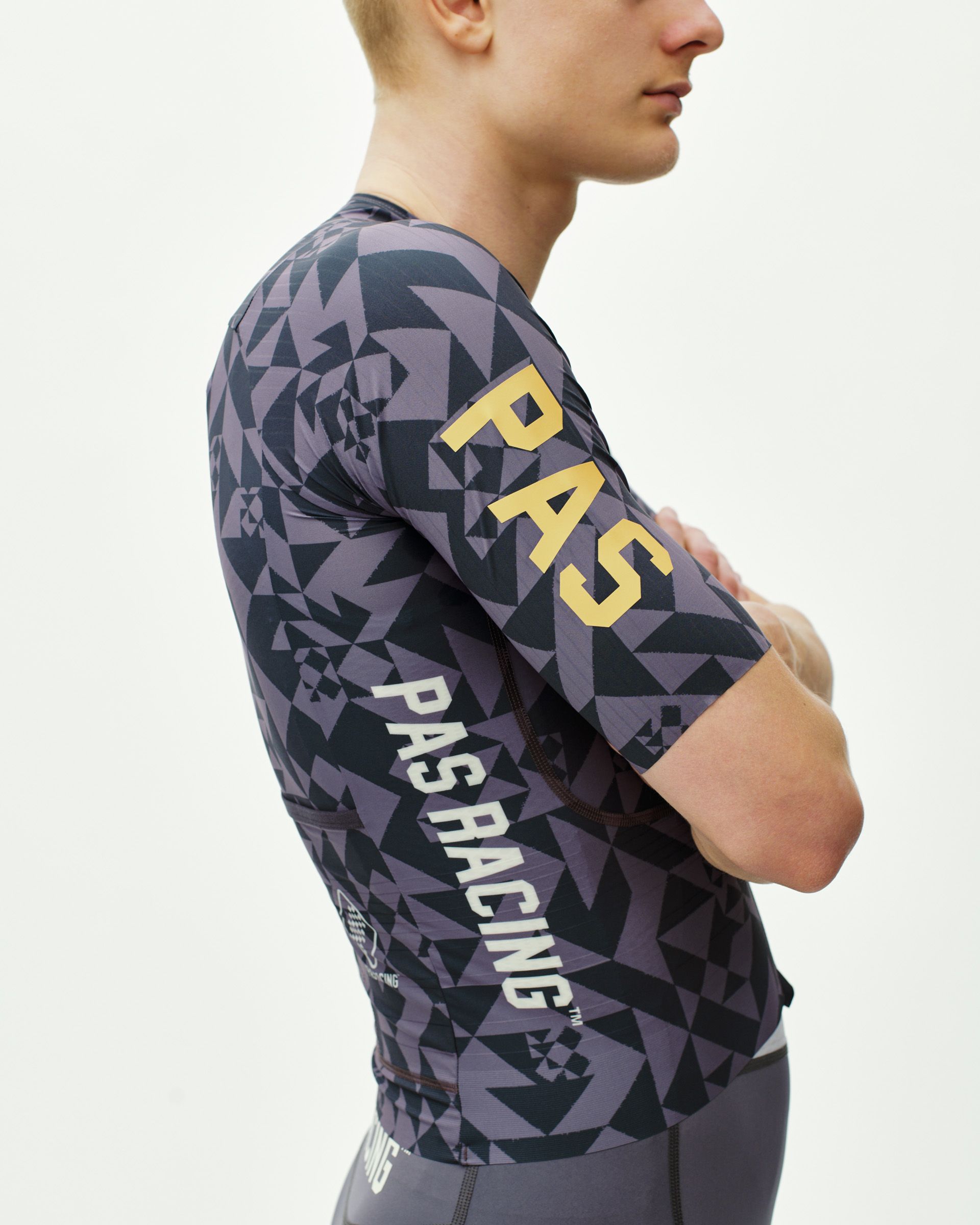 Origami Grey PAS Mechanism Pro cycling jersey on model, side view with geometric print and gold sleeve logo