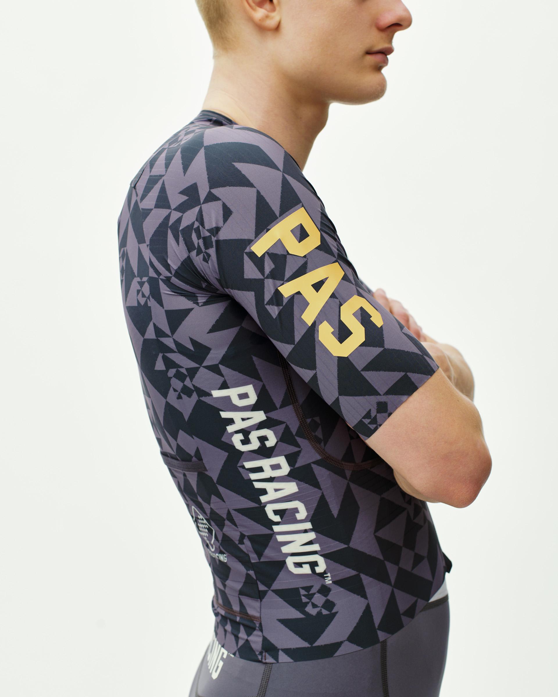 Origami Grey PAS Mechanism Pro cycling jersey on model, side view with geometric print and gold sleeve logo