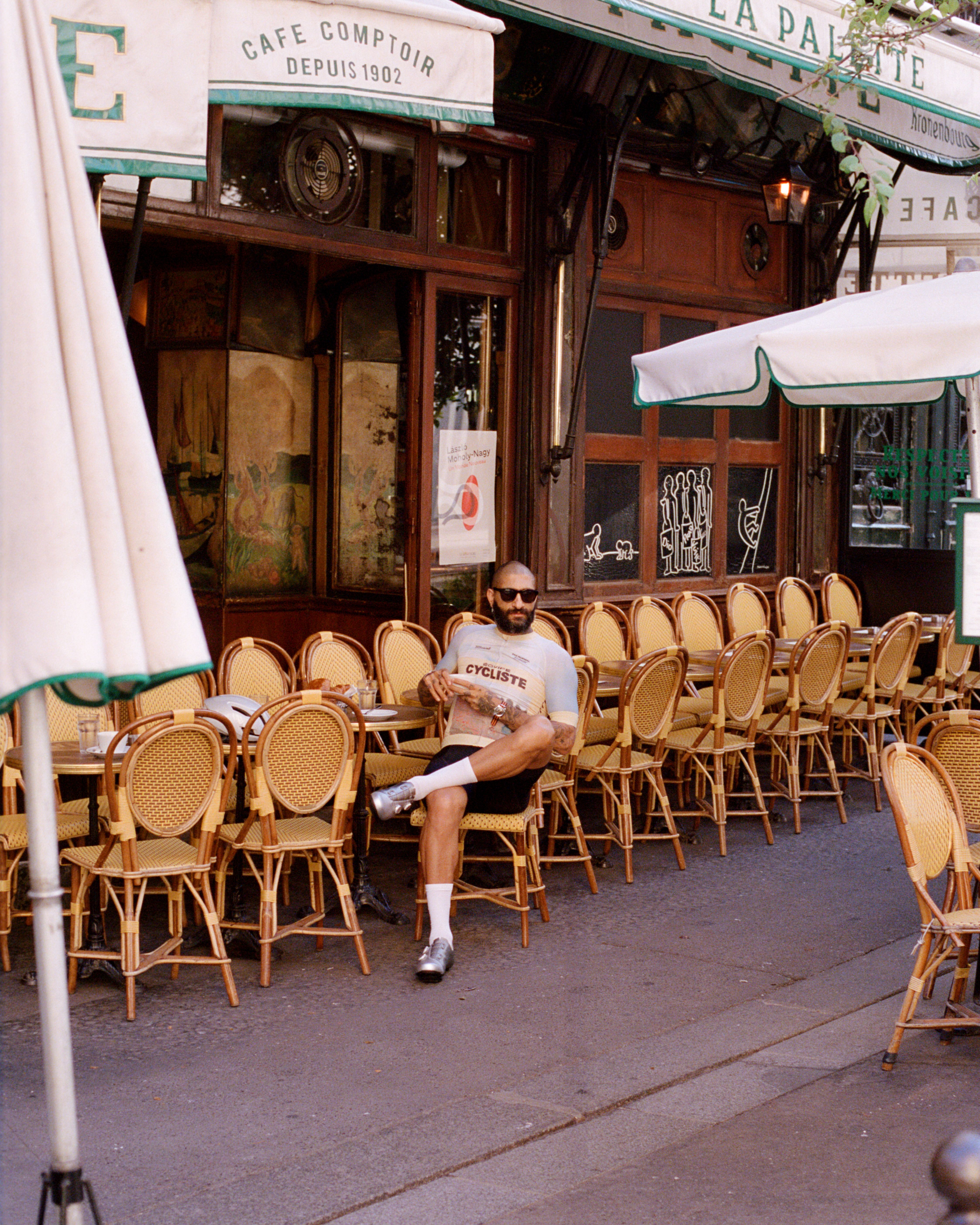 Model wearing white t-shirt with chest lettering sitting at Parisian cafe terrace