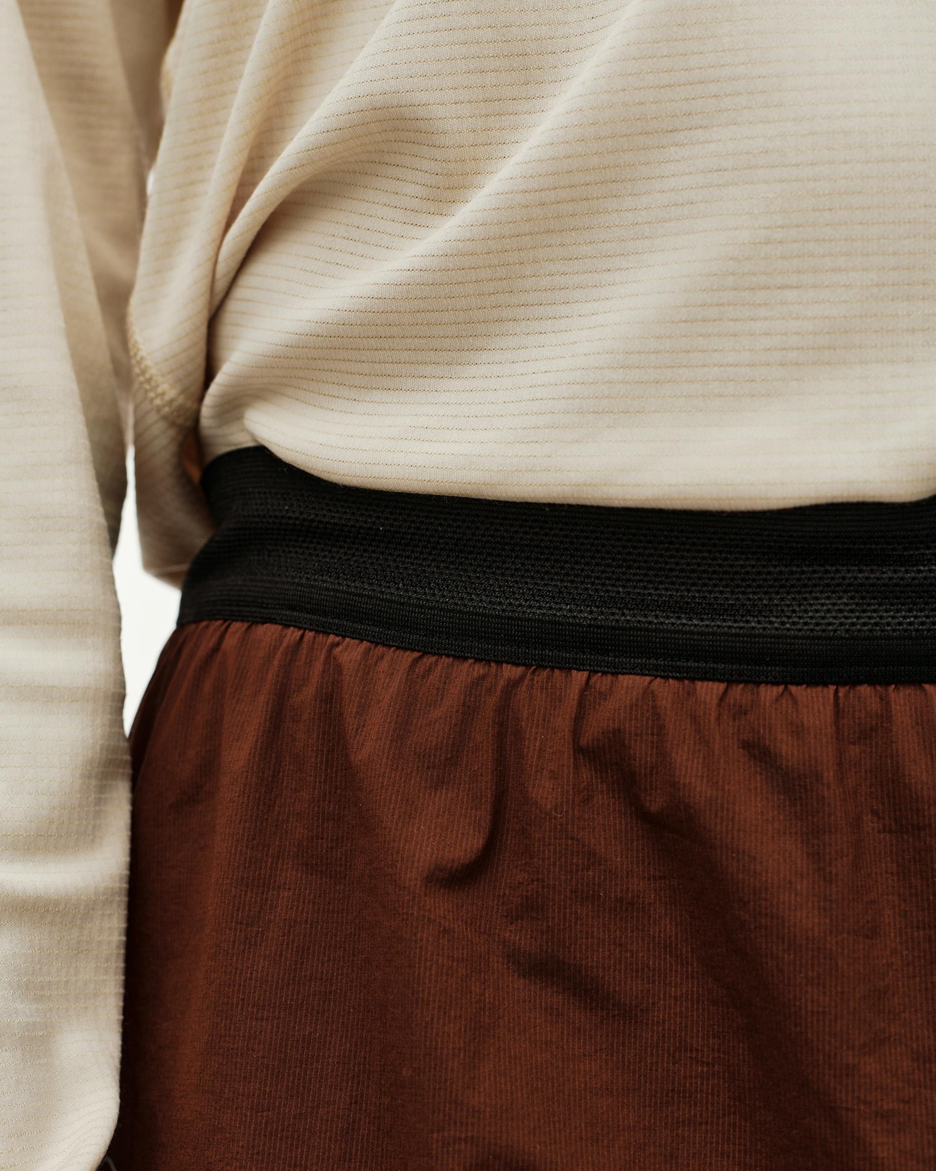 Maroon Brown Balance 2-in-1 shorts, detail view on model showing black elastic waistband and textured inner layer