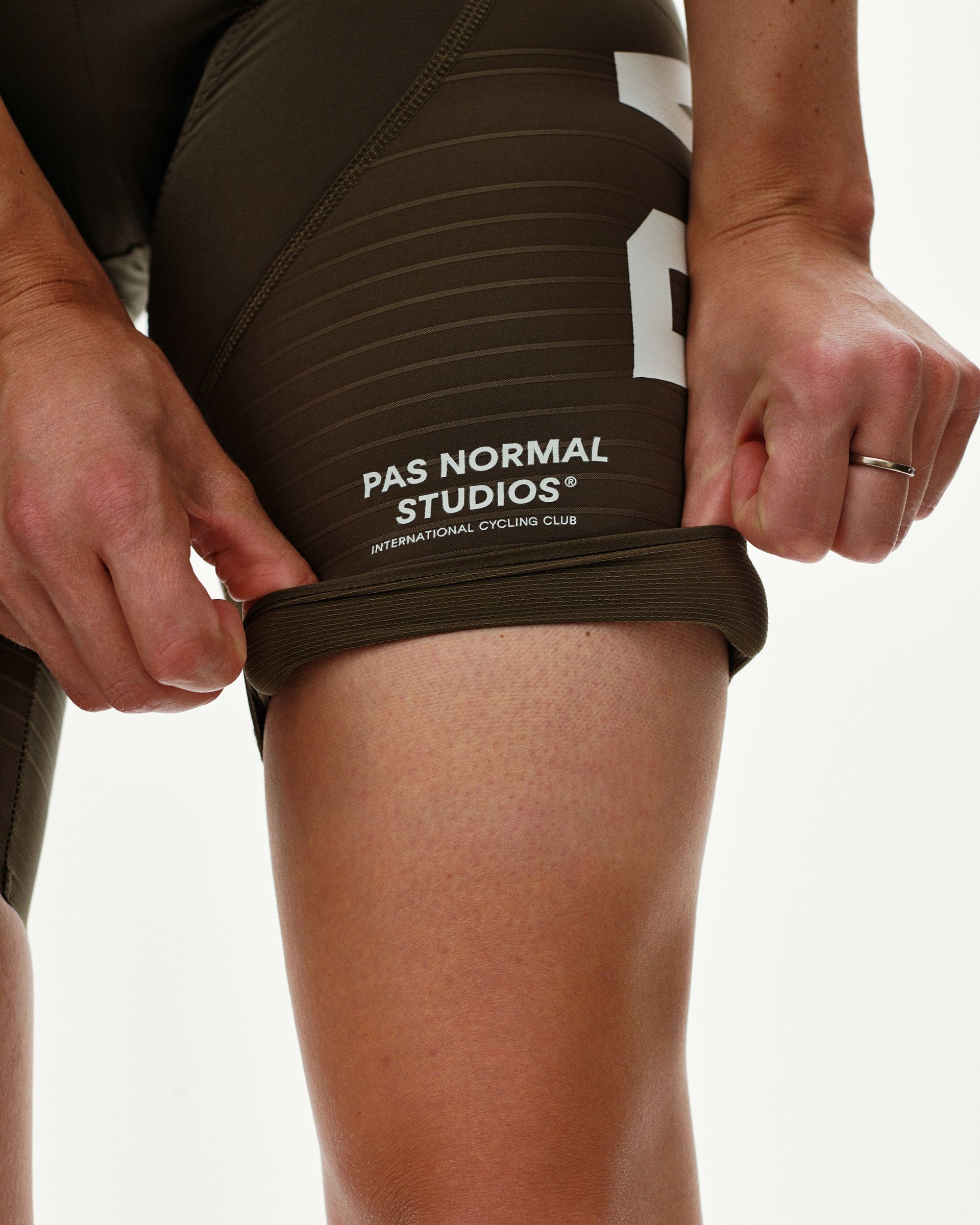 Dark Earth PAS Mechanism Pro women's cycling bibs, detail view showing ribbed leg gripper and white wordmark print