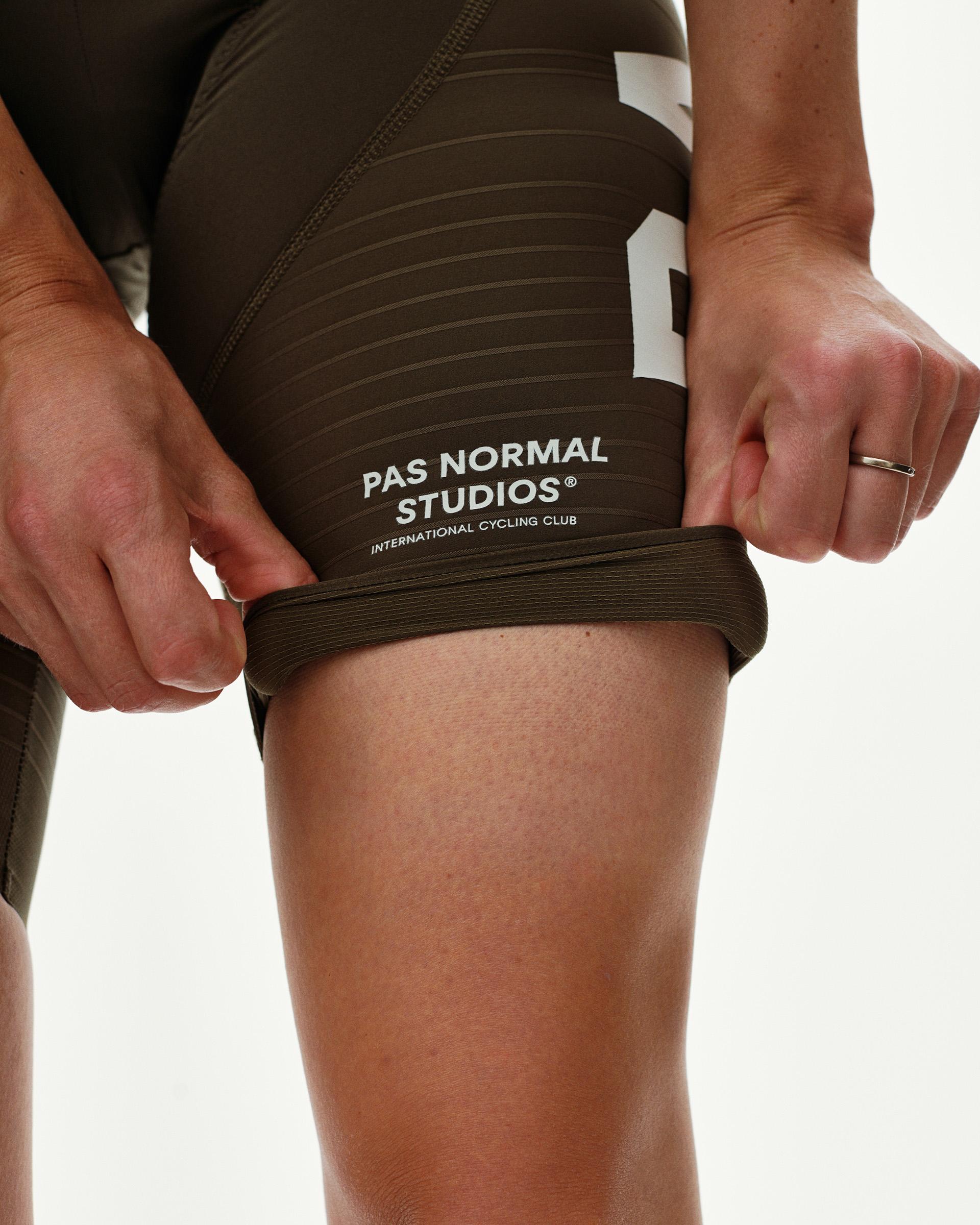 Dark Earth PAS Mechanism Pro women's cycling bibs, detail view showing ribbed leg gripper and white wordmark print