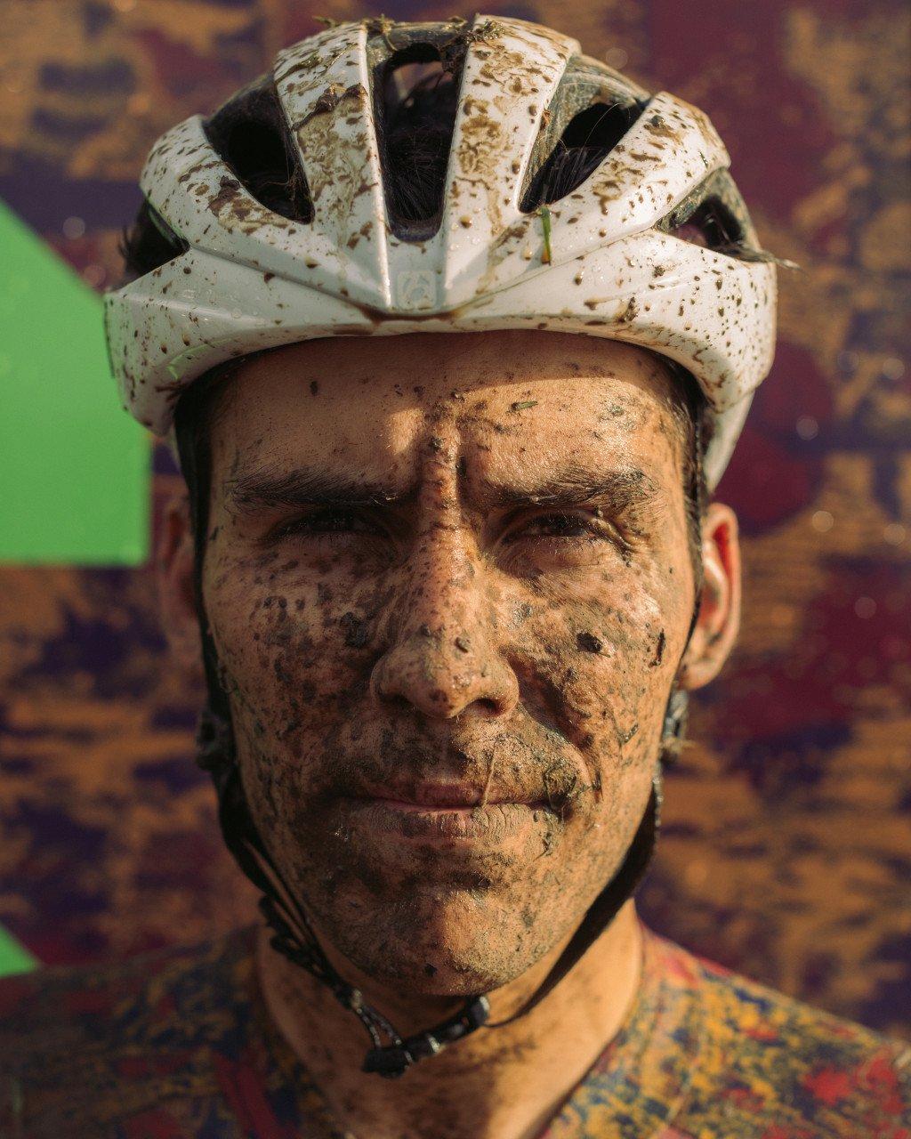 Cyclist with muddy face wearing white cycling helmet after race