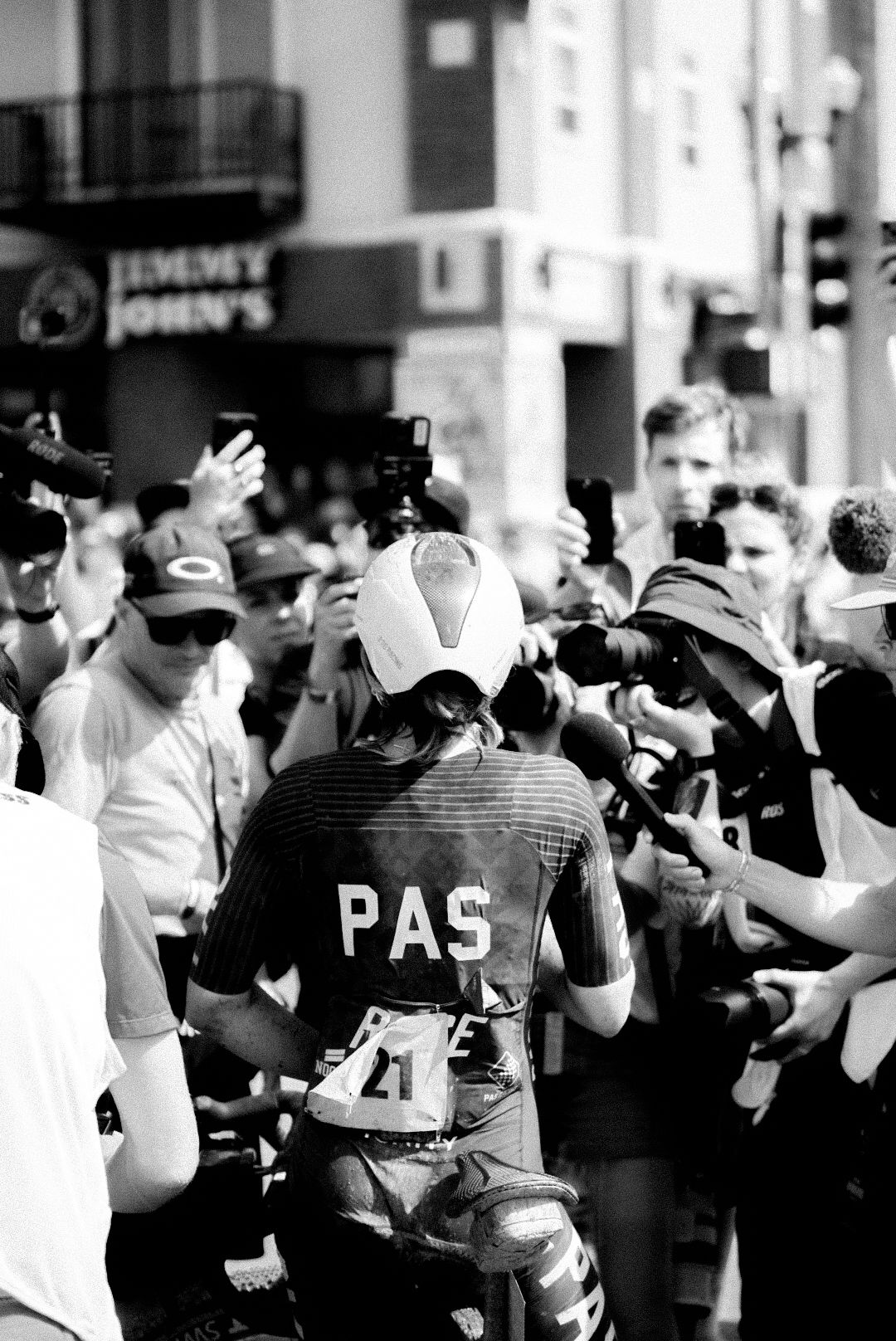 Cyclist in PAS collection jersey surrounded by crowd and media at gravel race event