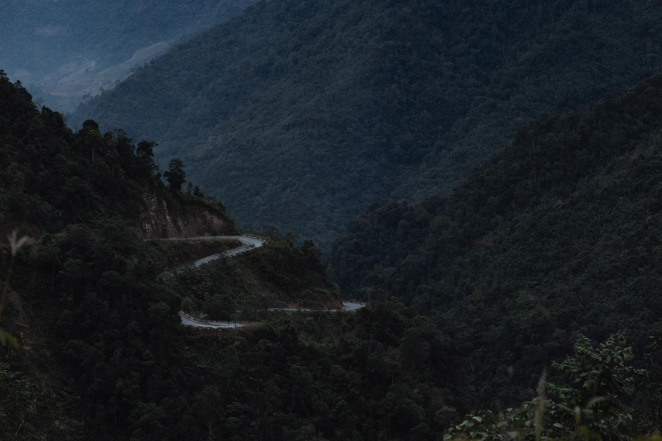 Winding mountain road through forested valley at dusk