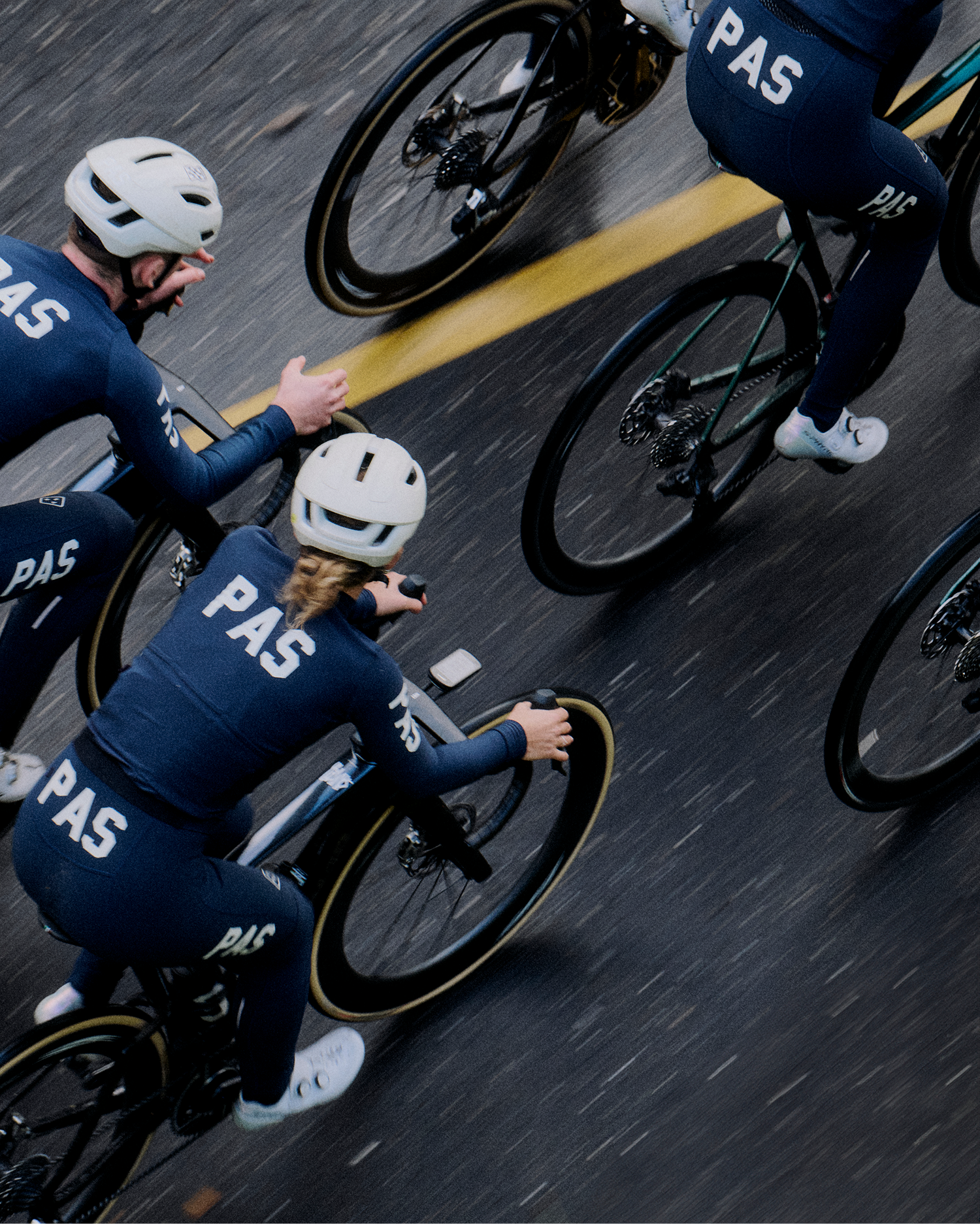 Models wearing navy PAS collection cycling kit with logo branding on velodrome track