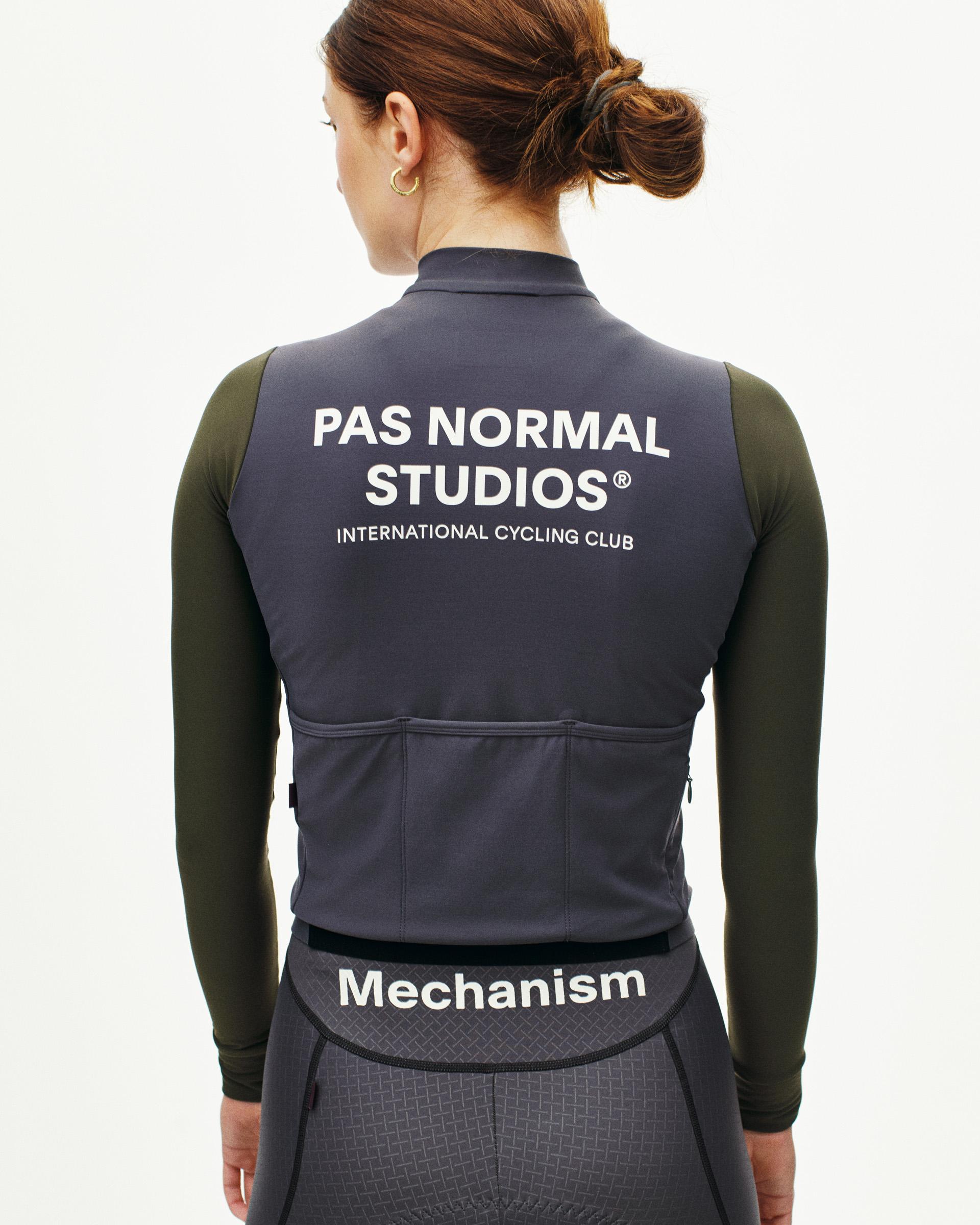 Grey Mechanism long sleeve cycling jersey on model, rear view with white back logo and olive sleeves