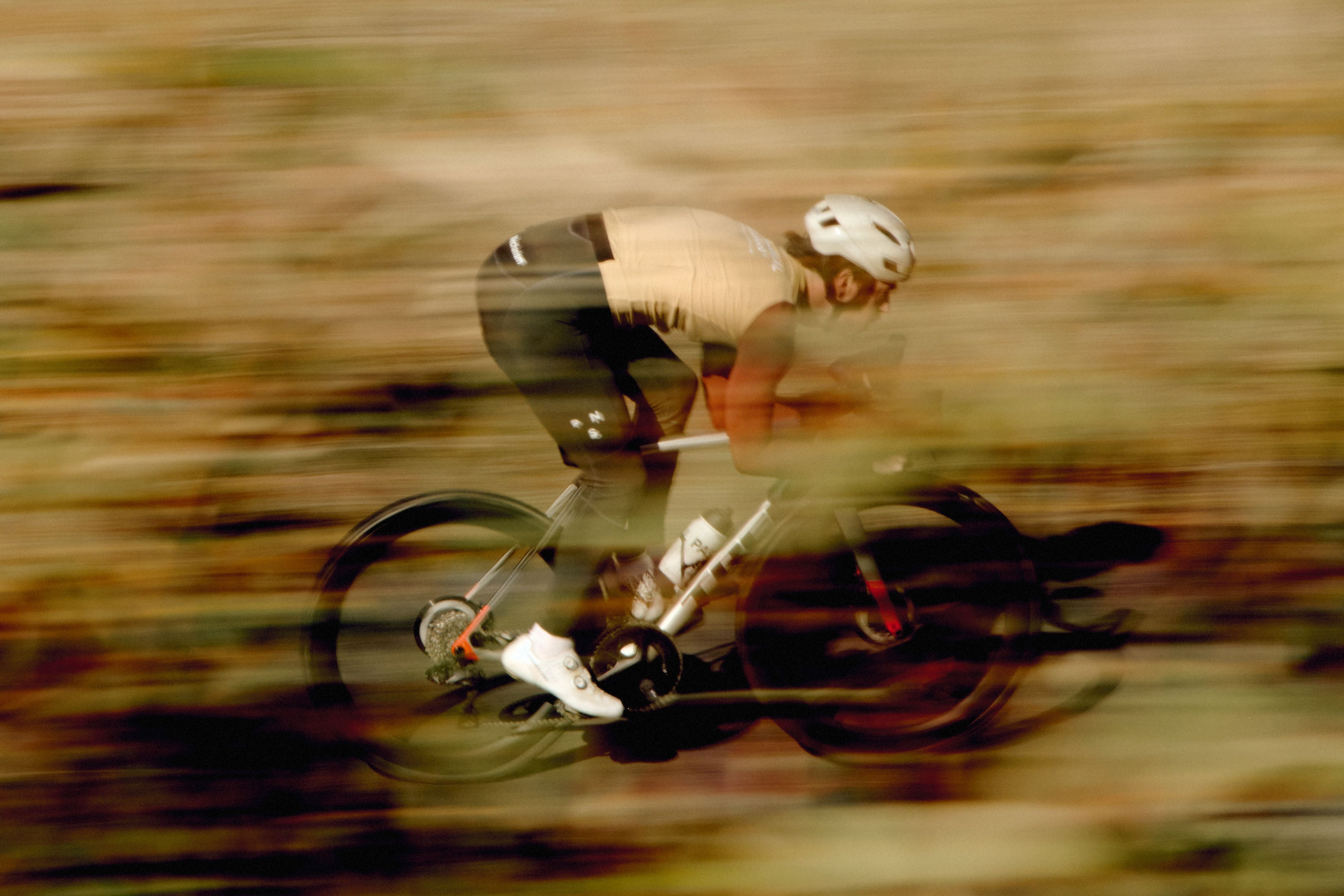 Cyclist in aerodynamic position on time trial bike with motion blur background