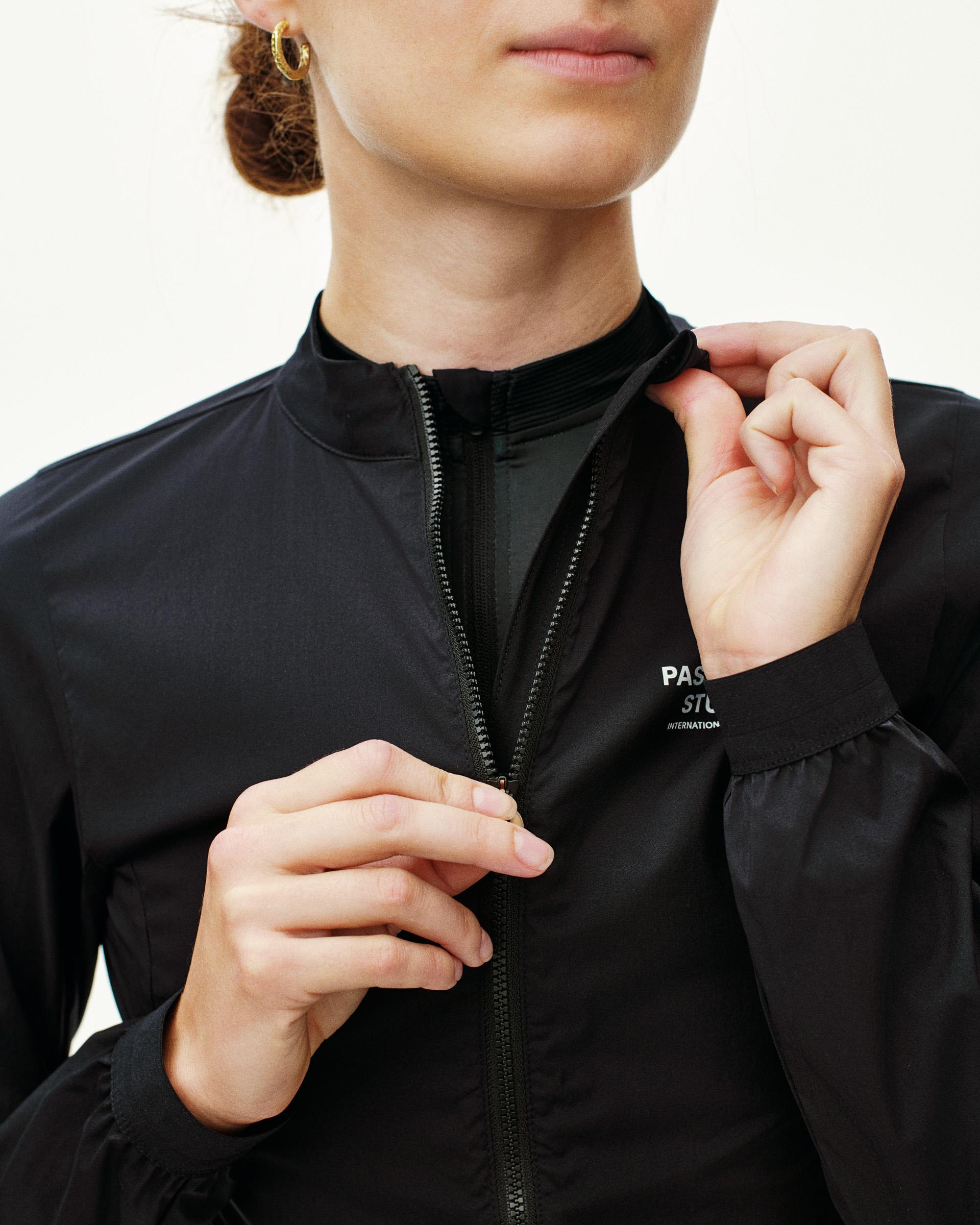 Black Mechanism Stow Away jacket on model with half zip and white chest logo